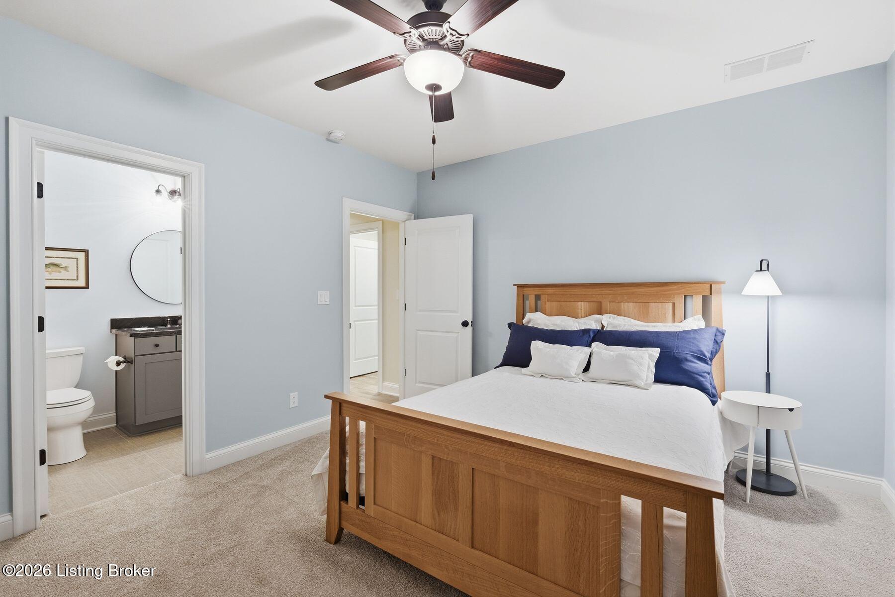 Bedroom with a wooden bed and navy pillows, adjoining an ensuite bathroom.