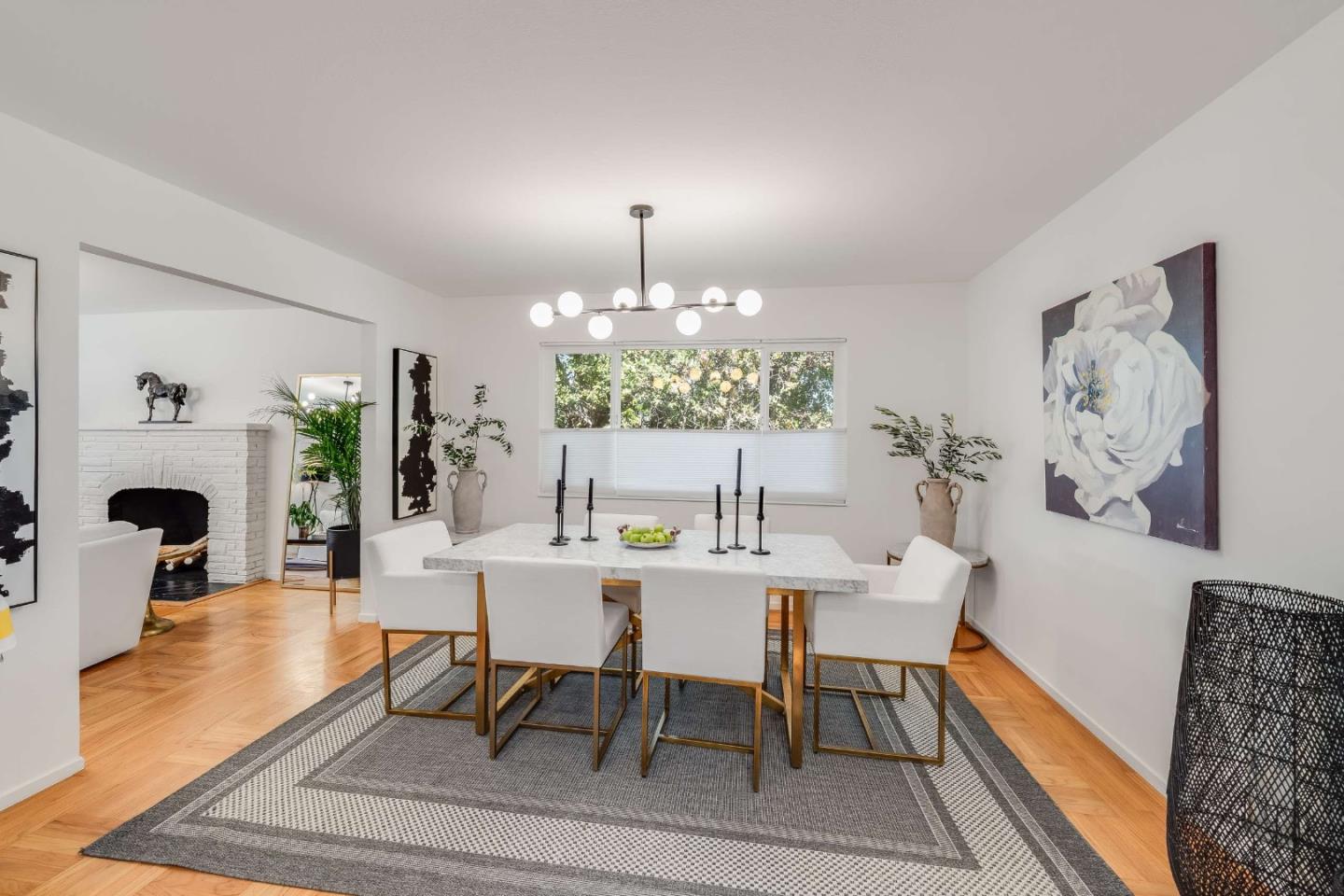 Dining room with a globe chandelier, patterned rug, and white brick fireplace.