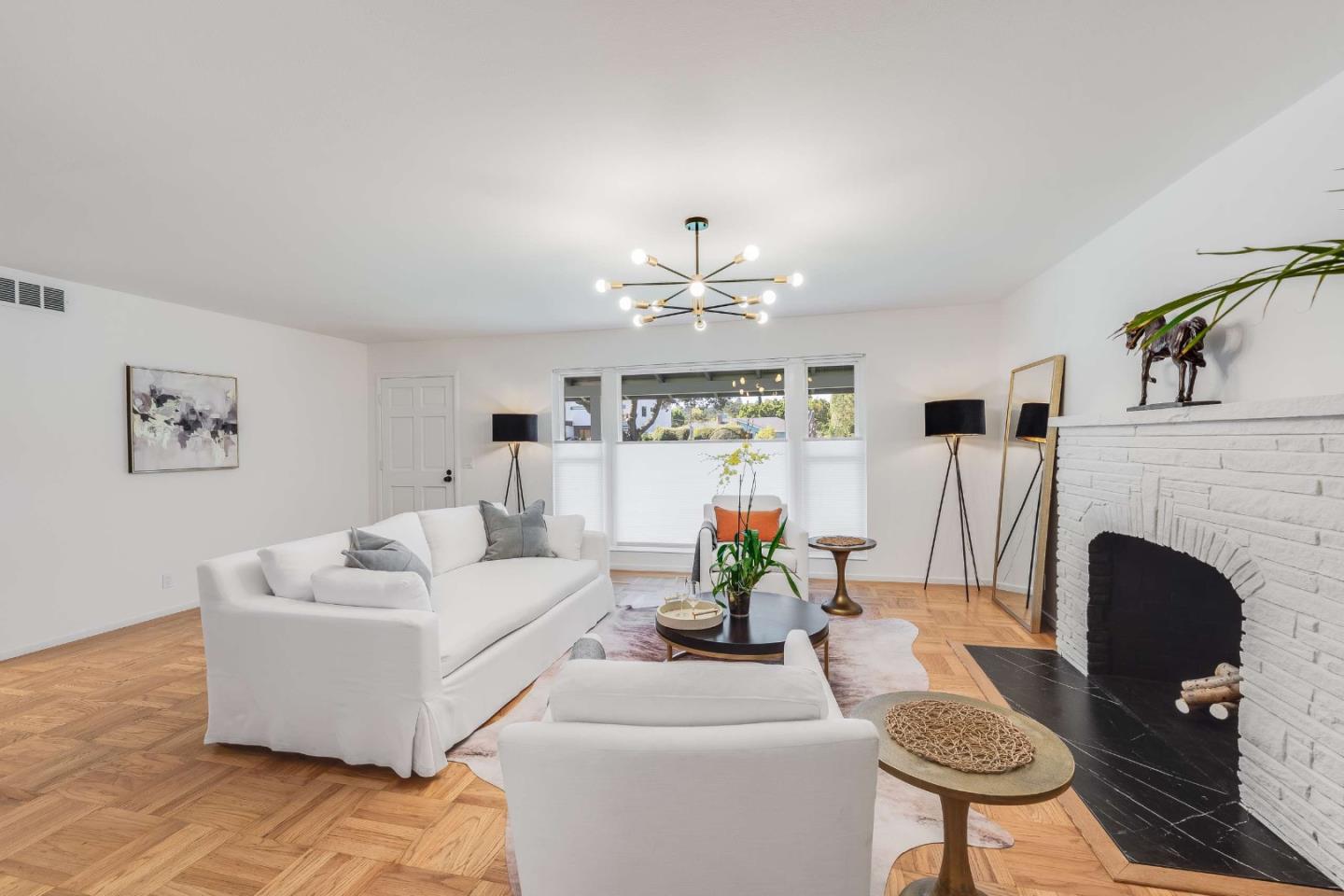 Staged living room with white sofas, a brick fireplace, and parquet floors.