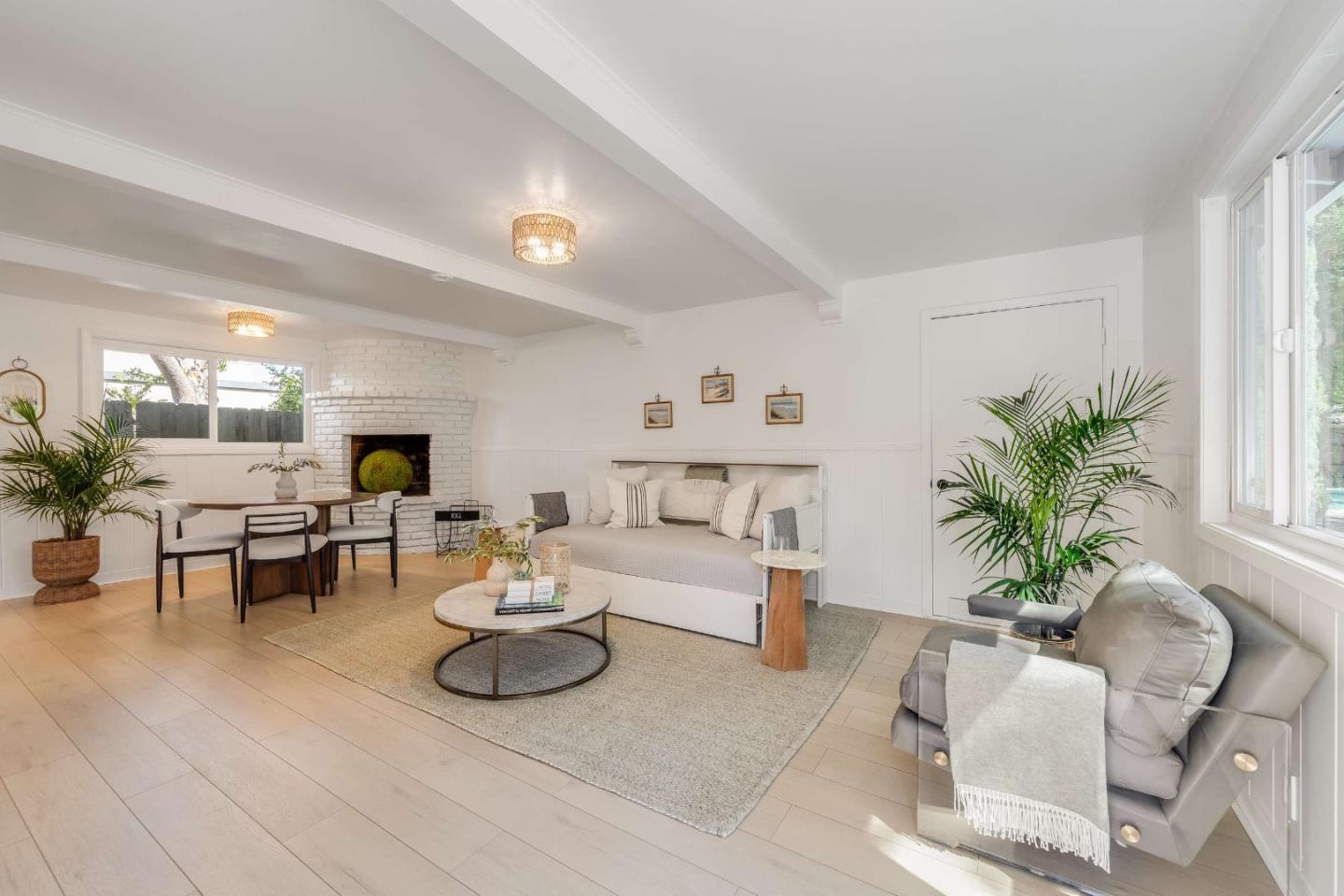Bright living room with a white brick fireplace, dining nook, and large windows.