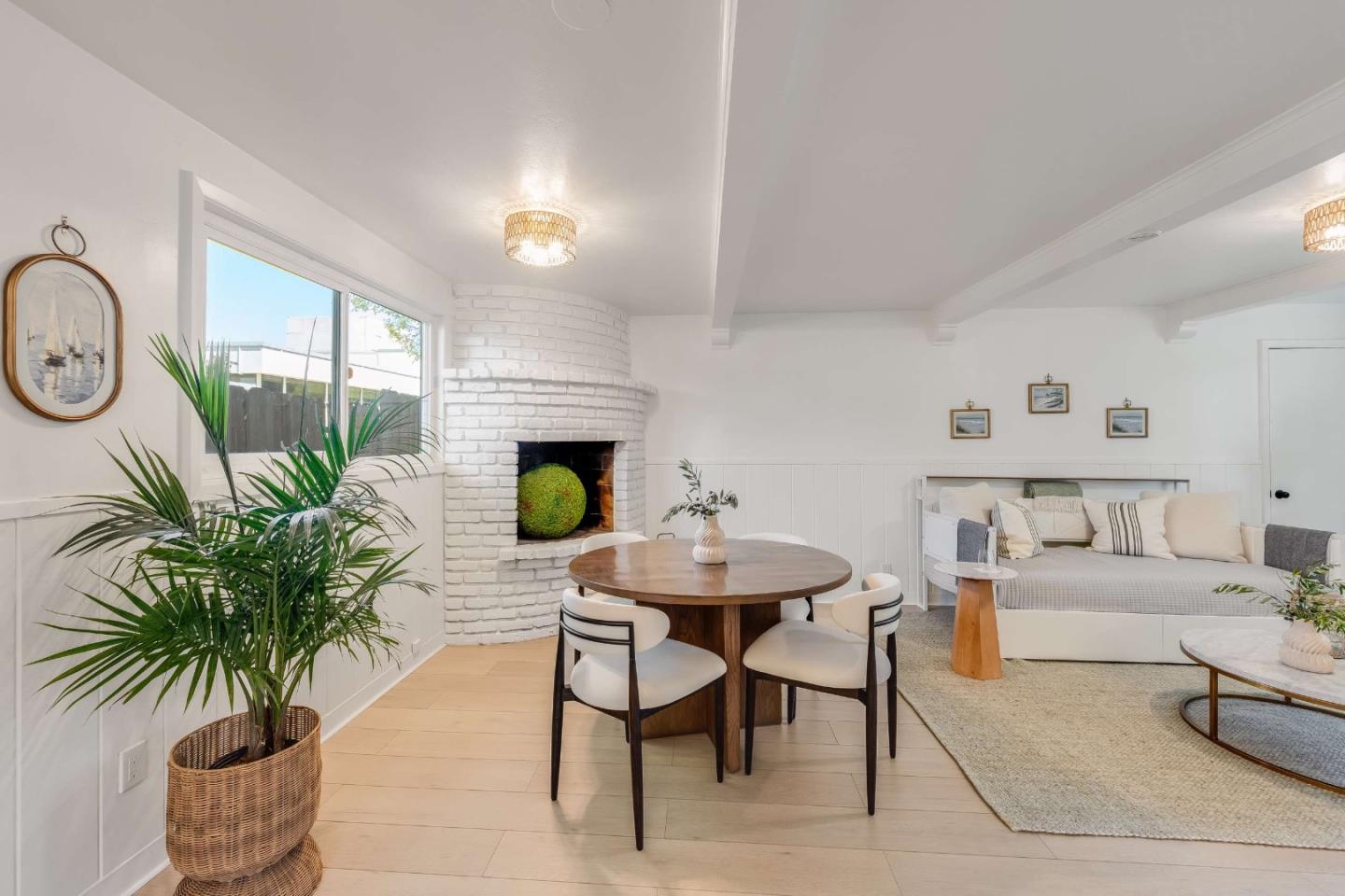 Staged living and dining room with a white brick fireplace and round wooden dining table.