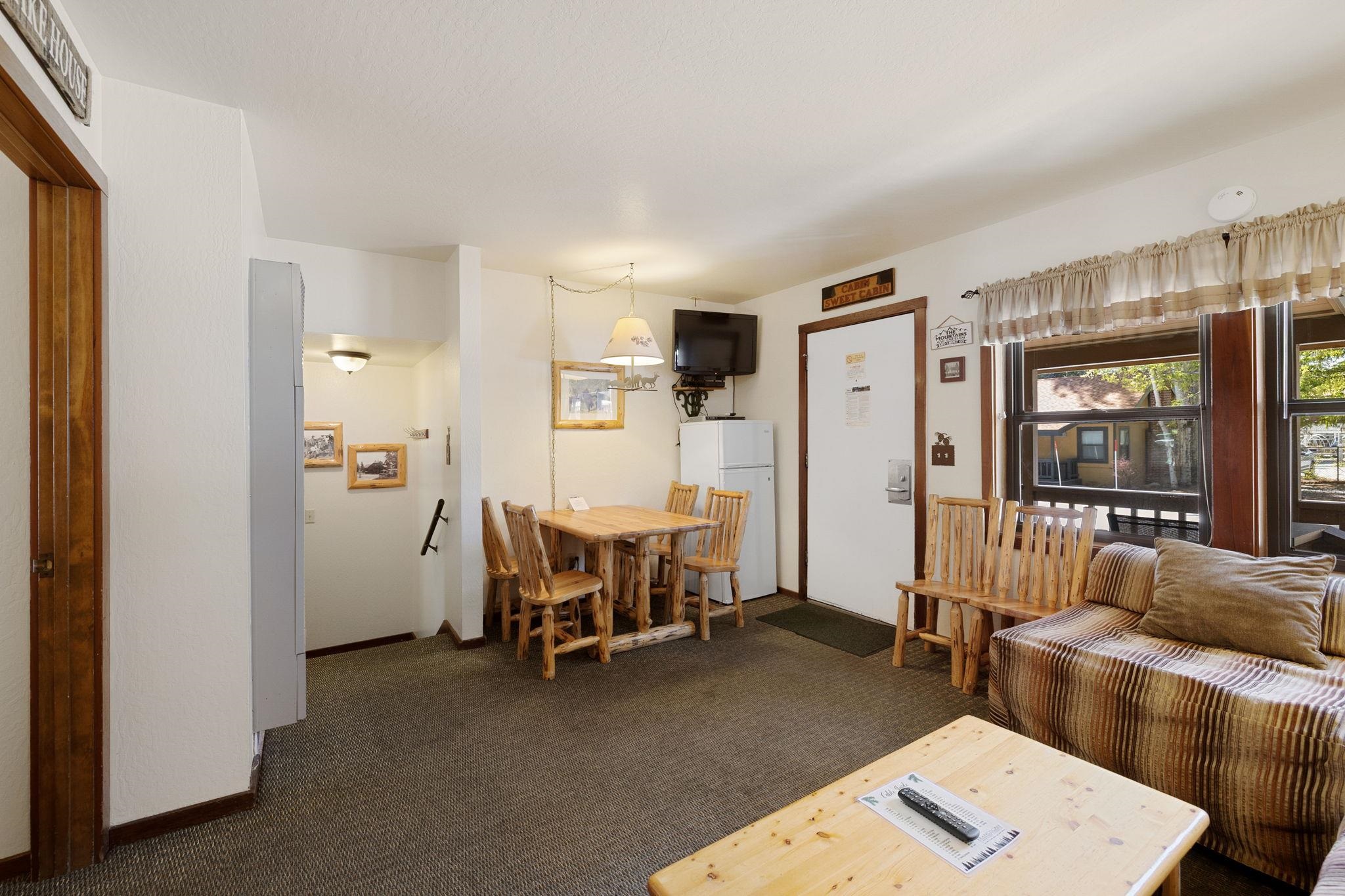 Furnished cabin living and dining area with rustic wood furniture and large windows.