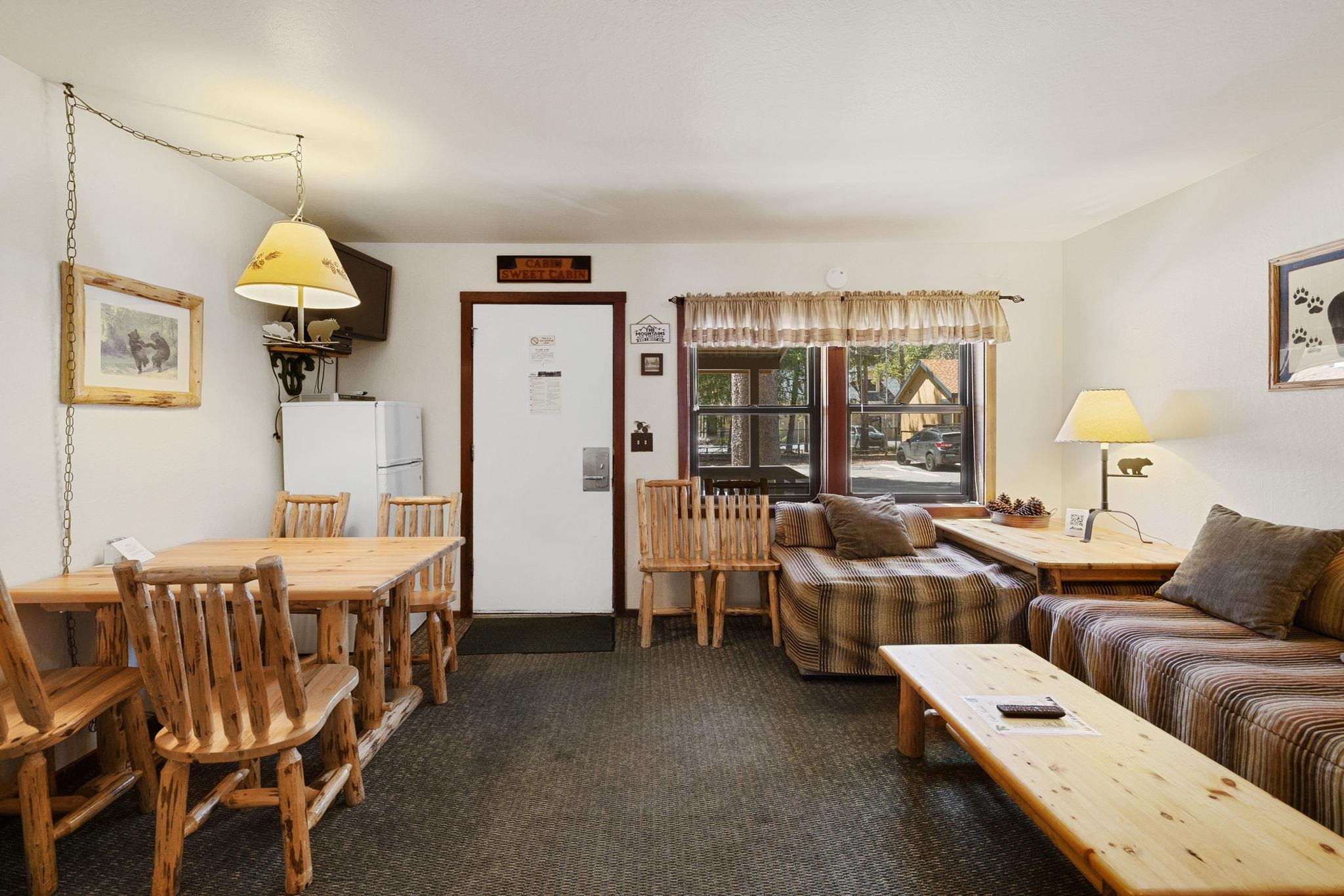 Cabin-style living and dining room with rustic log furniture and striped sofas.
