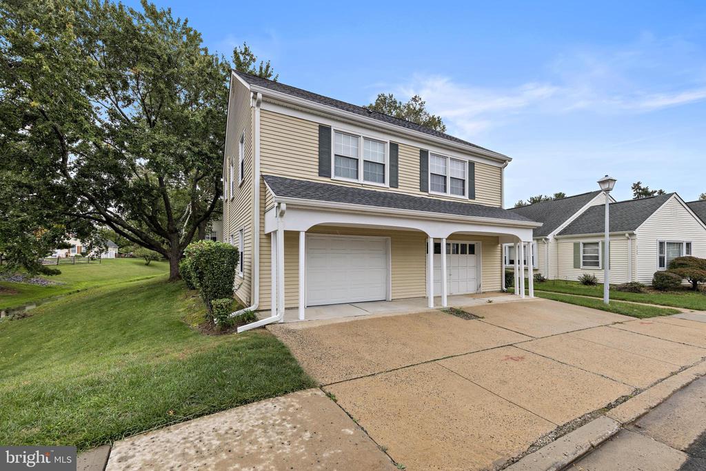 Beige two-story townhouse with covered parking, two garage doors, and a wide driveway.