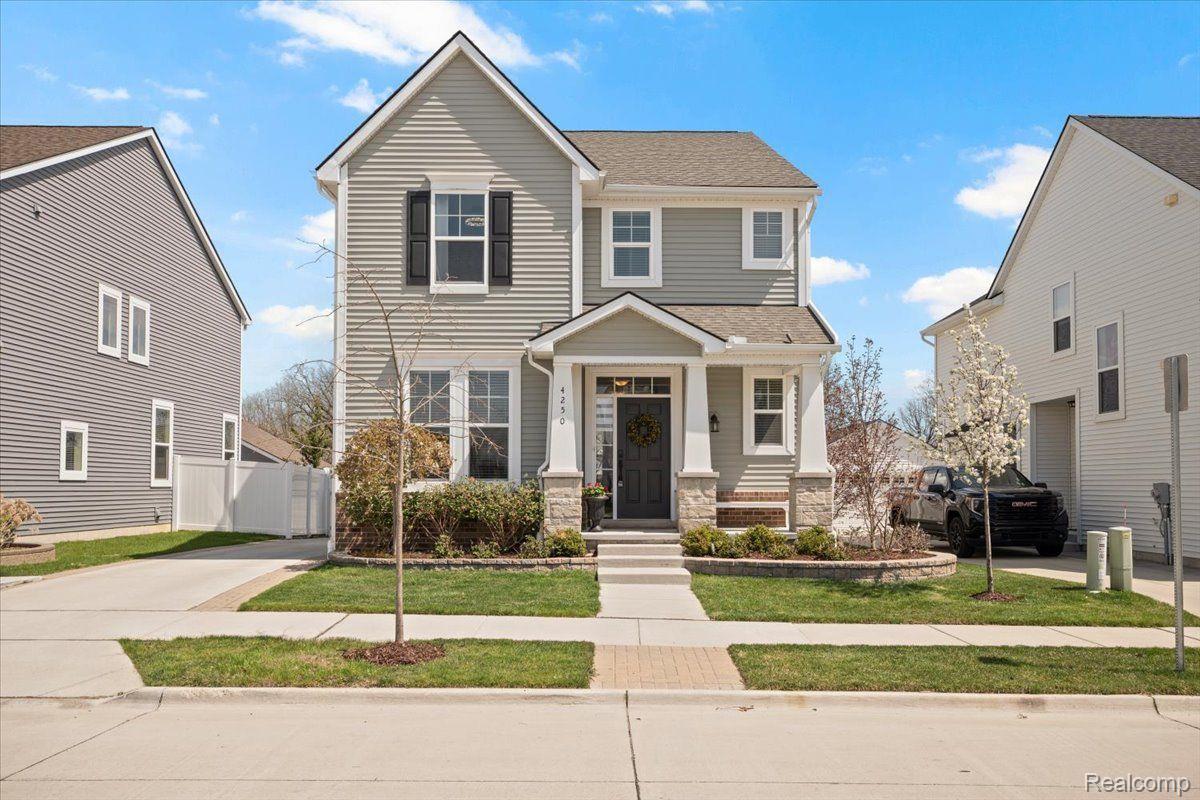 Two-story gray-sided home with a covered entry, landscaped front garden, and black pickup truck in the driveway.