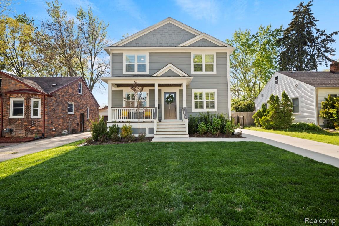 Two-story gray home with white trim, a covered front porch, and a broad green lawn.