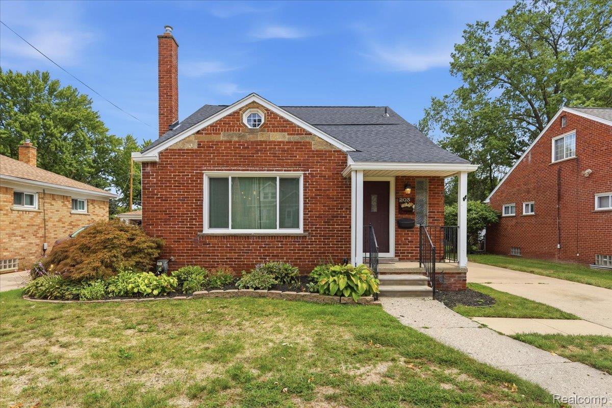 Red-brick house with a covered porch, tall chimney, and landscaped front garden.