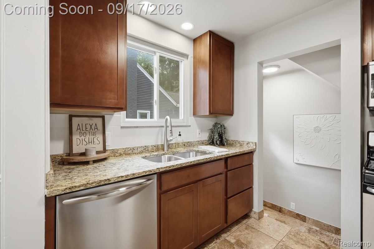 Kitchen with dark wood cabinets, granite counters, and a double-basin sink beneath a window.