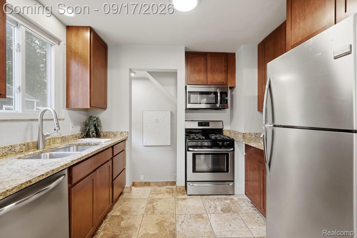 Kitchen with wood cabinets, granite counters, stainless steel appliances, and a sink beneath the window.