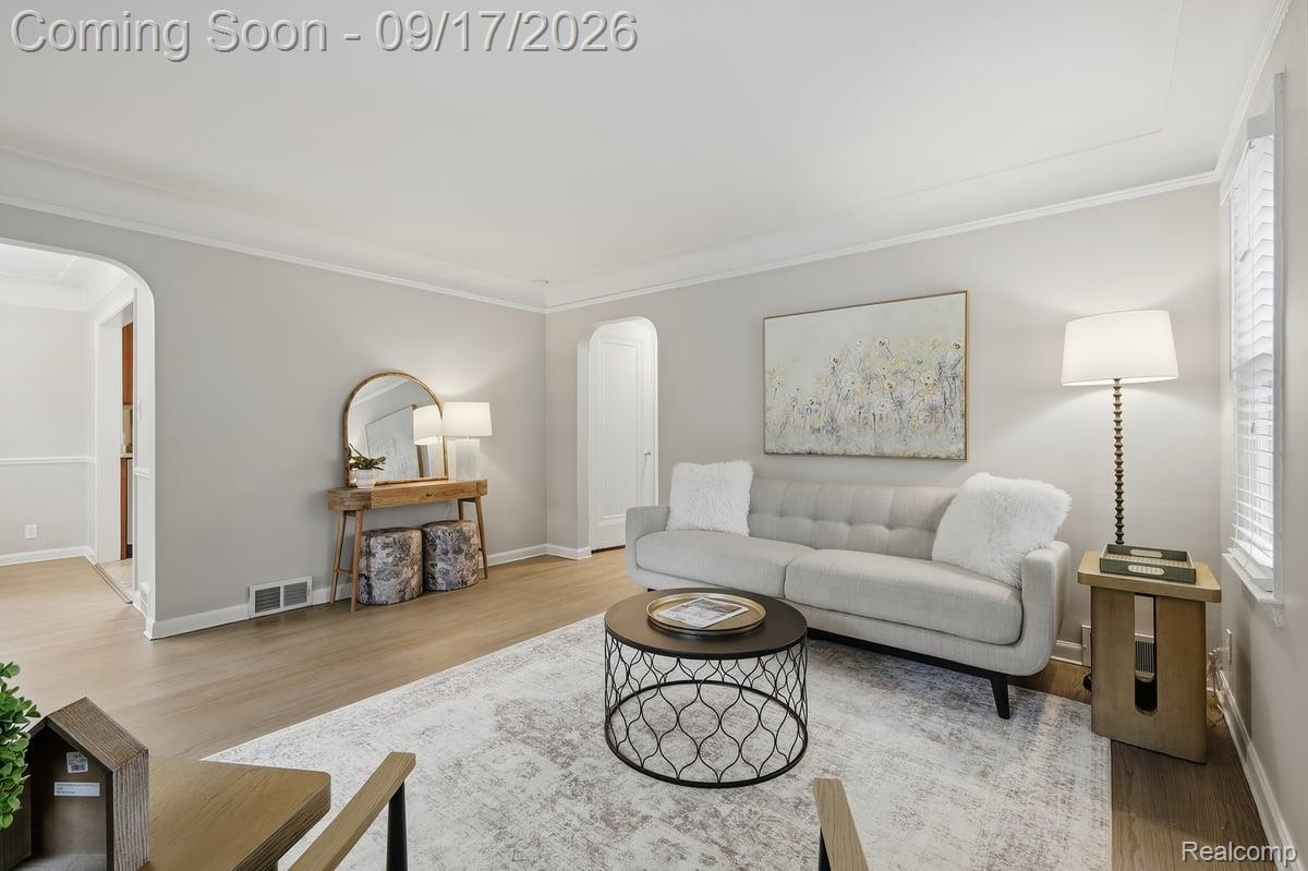Staged living room with a gray sofa, round coffee table, pale rug, and arched mirror.