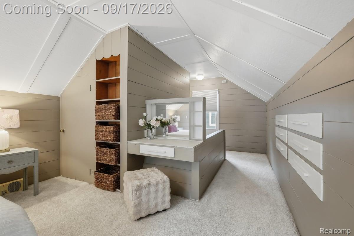 Attic bedroom with sloped ceilings, built-in vanity, shelving, and white carpet.