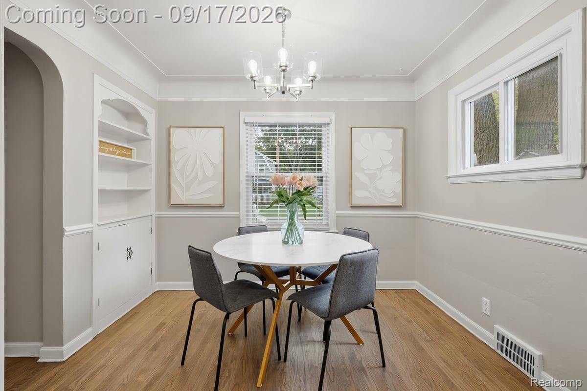Dining room with a round white table, gray chairs, built-in shelving, and pink tulips.