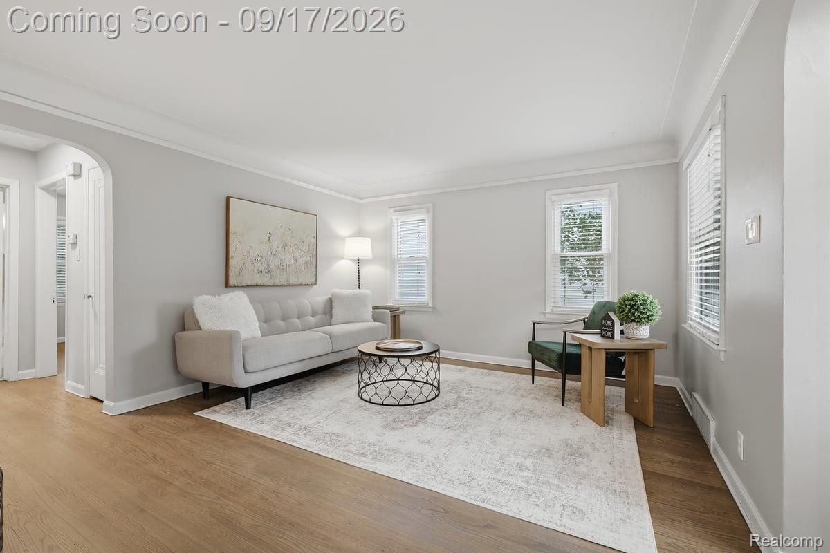 Staged living room with a tufted sofa, round coffee table, and bright windows.