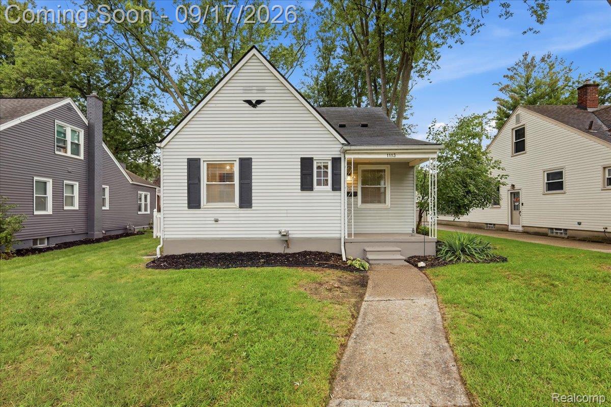 White single-story home with dark shutters, a steep front gable, and a concrete walkway across the lawn.