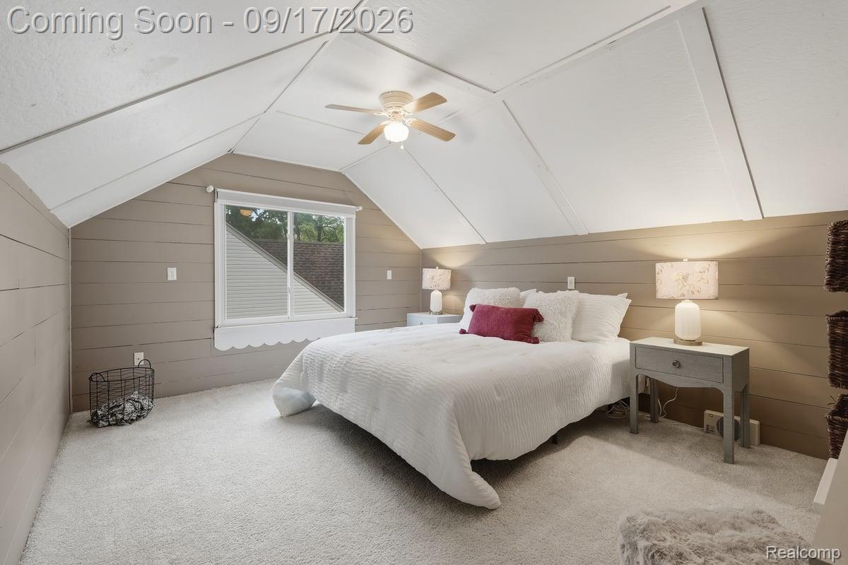 Attic bedroom with a vaulted ceiling, white bed, burgundy accent pillow, and window.