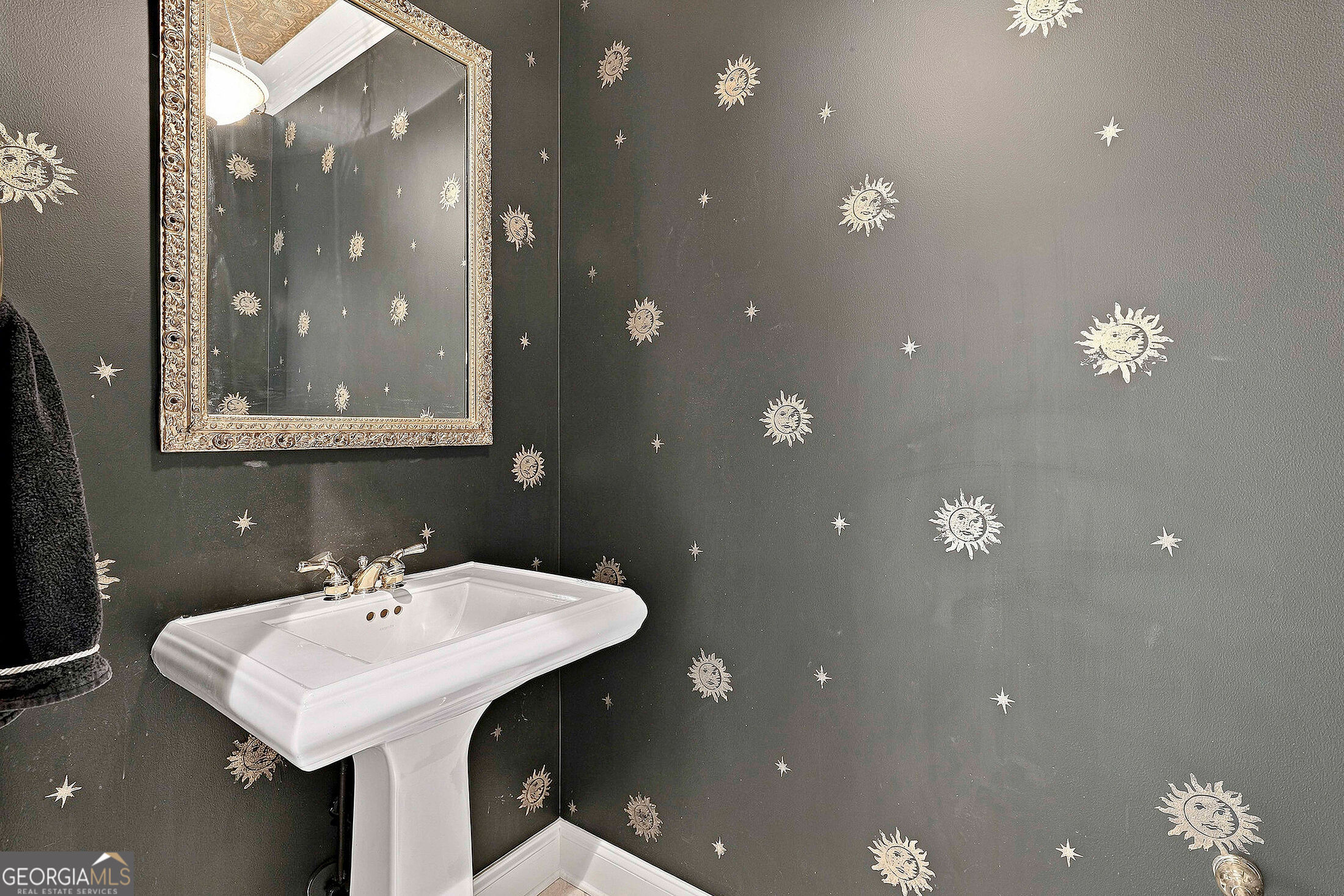 Powder room with a white pedestal sink and sun-and-star wallpaper.