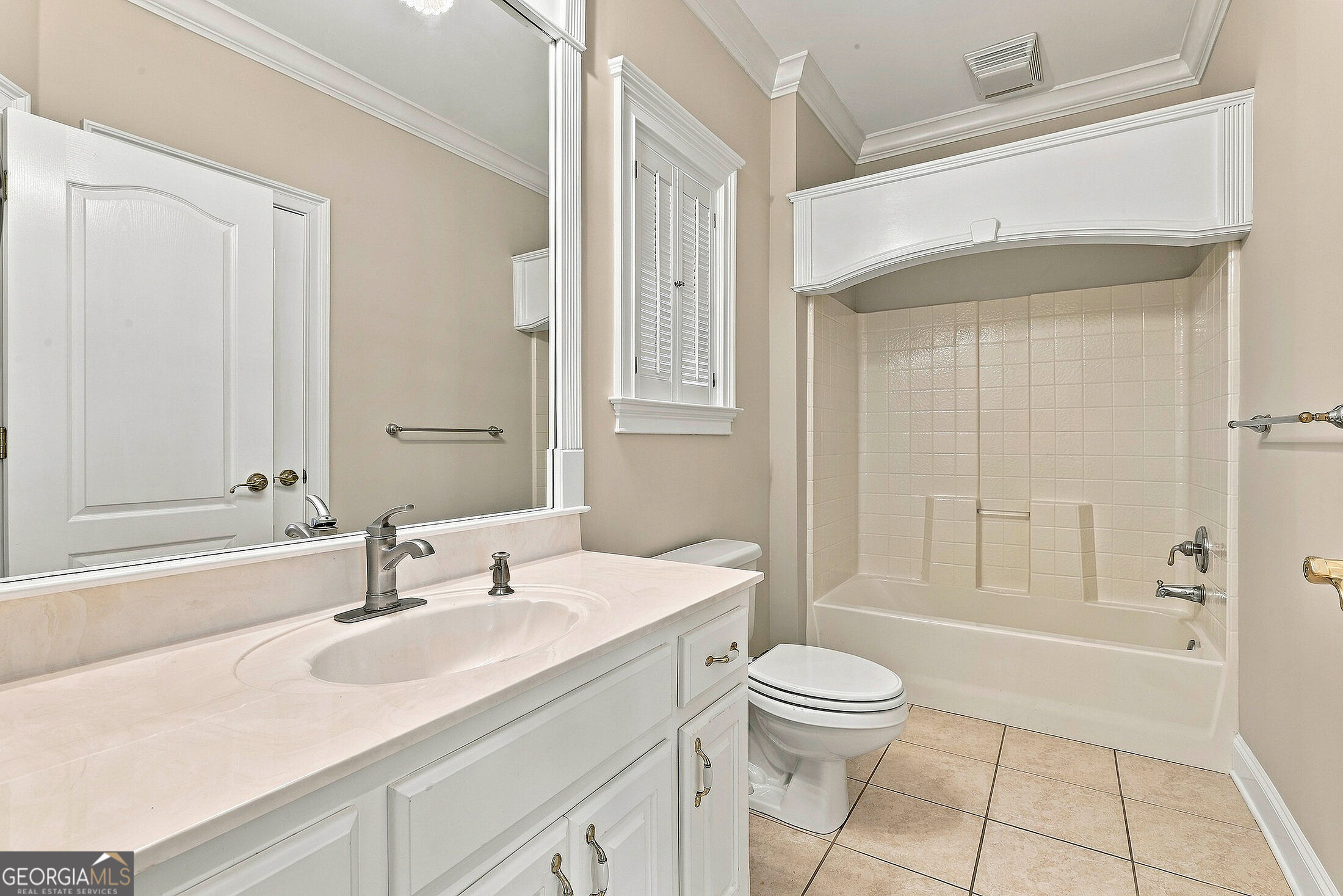 Bathroom with a white vanity, tiled tub-shower alcove, built-in seat, and shuttered window.