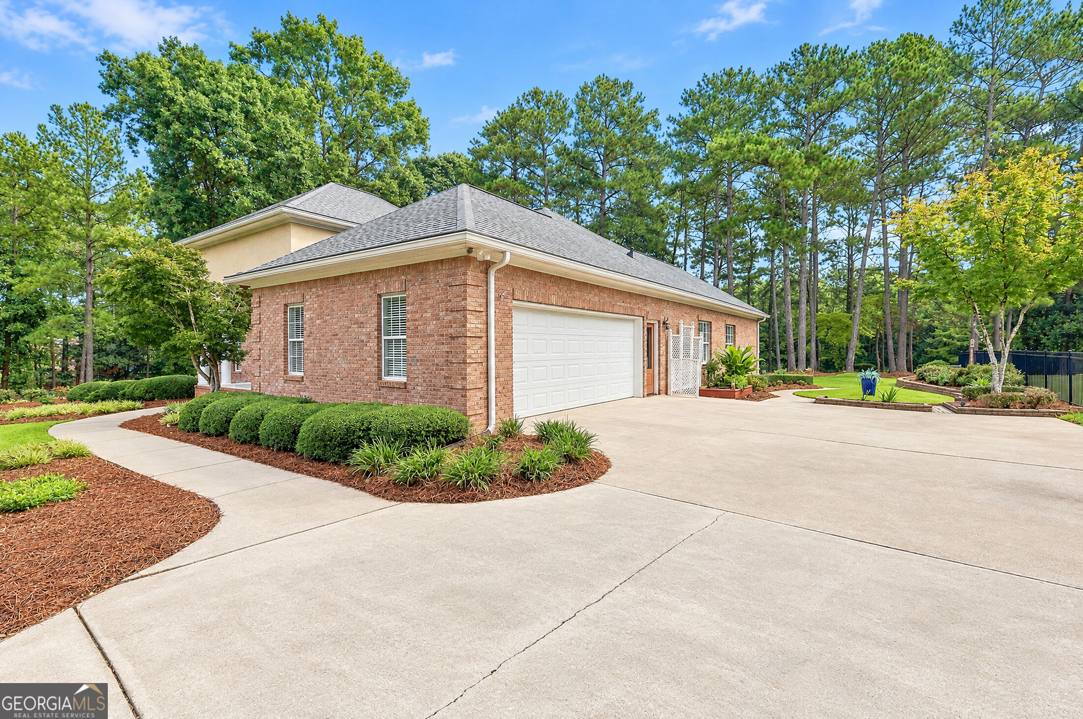 Red brick home with a two-car garage, wide driveway, and landscaped yard.