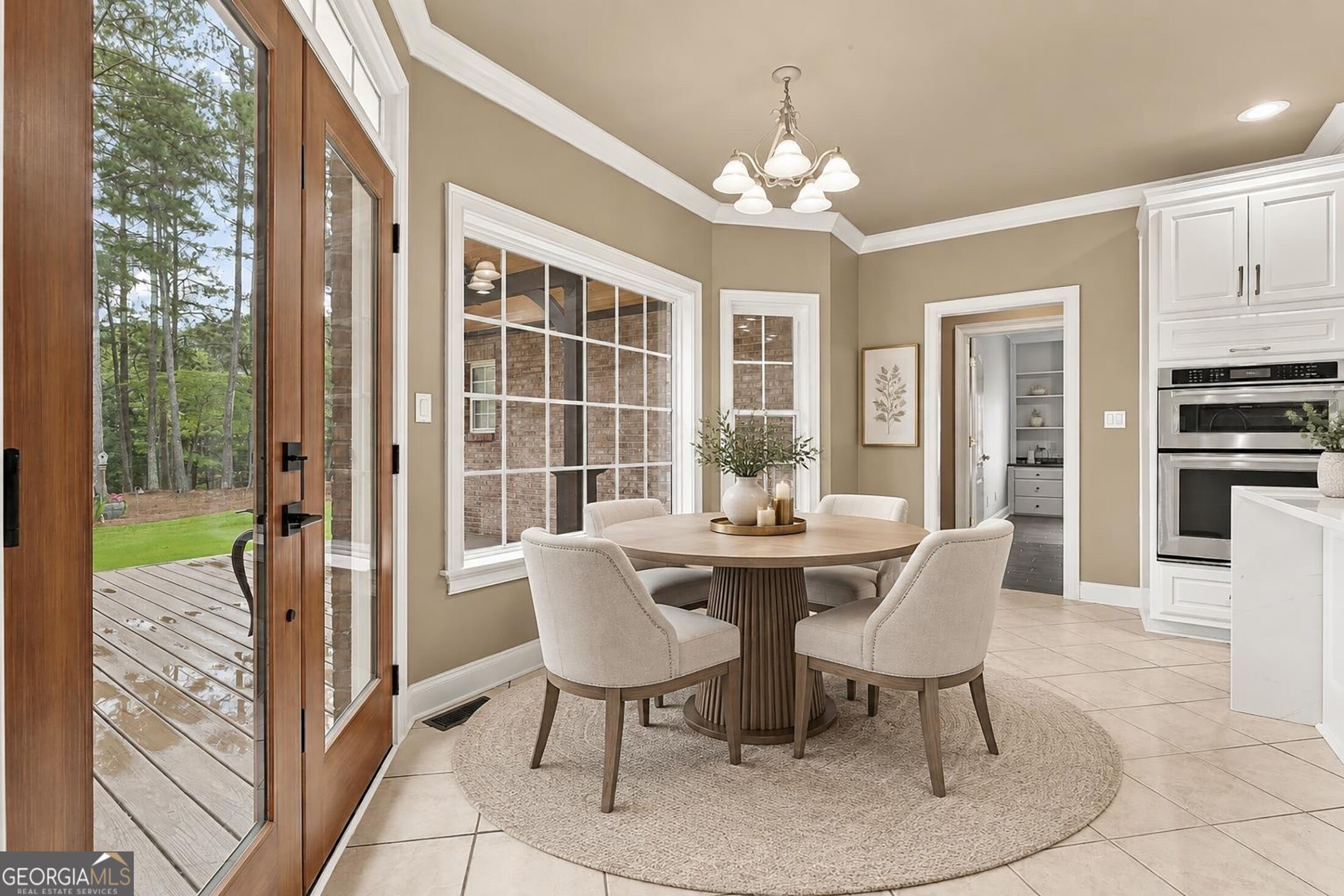 Dining area with a round table and chairs beside tall windows and a glass door to the deck.