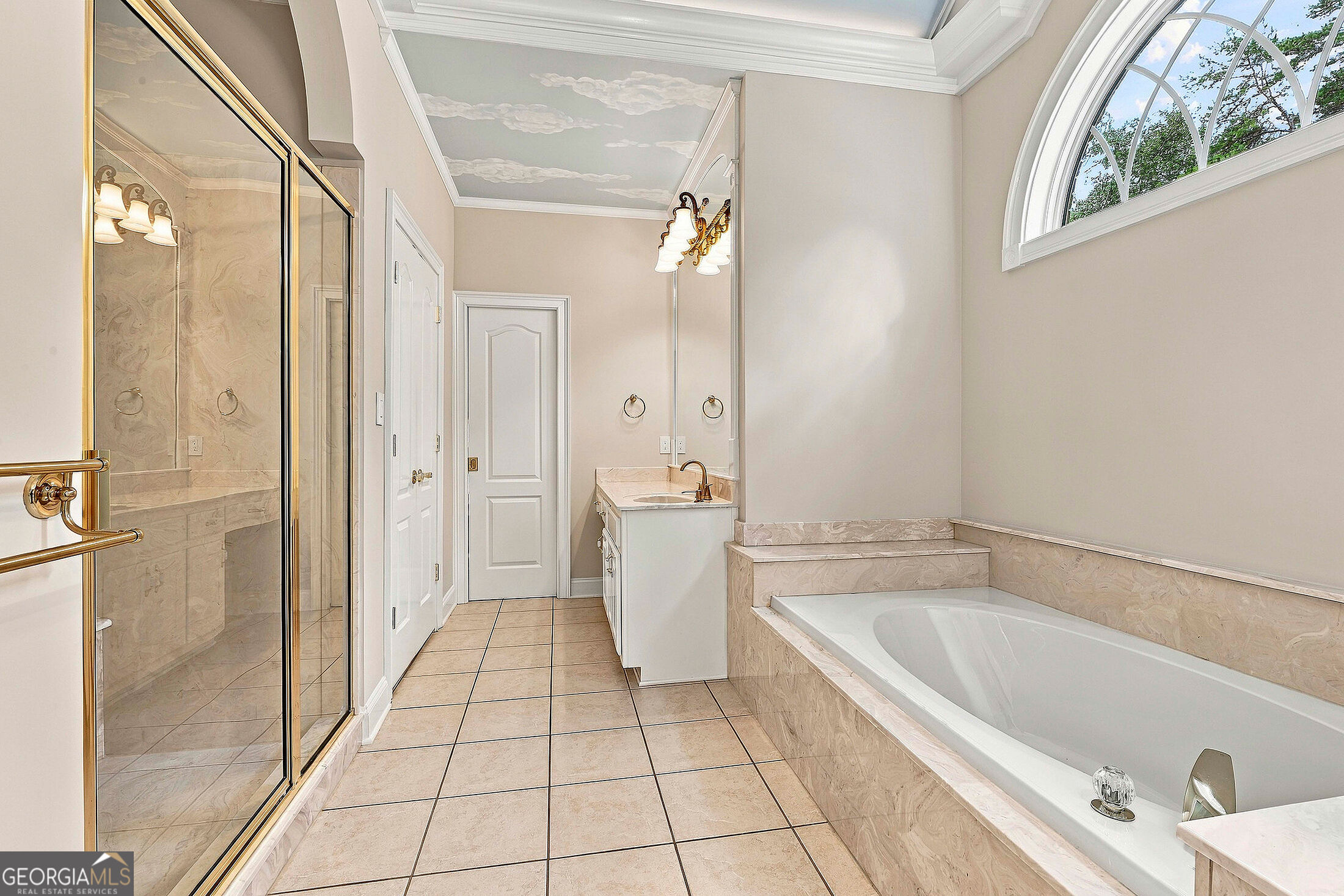 Primary bathroom with a marble shower, built-in soaking tub, and large arched window.