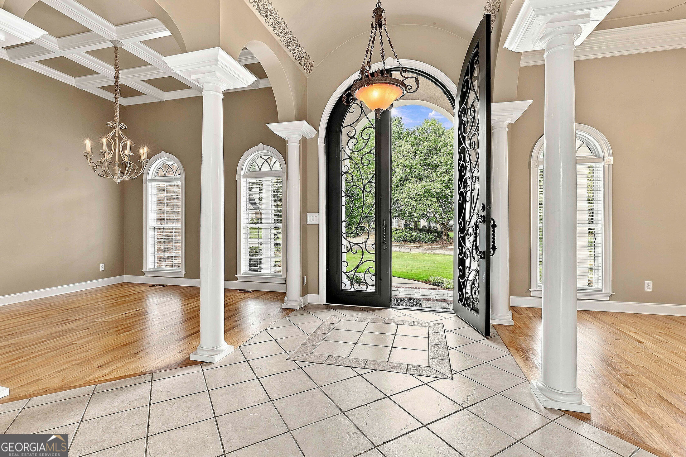Foyer with tiled entry, white columns, and an open wrought-iron front door.