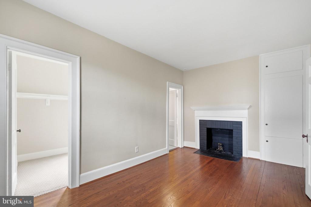 Empty room with hardwood floors and a dark tiled fireplace.