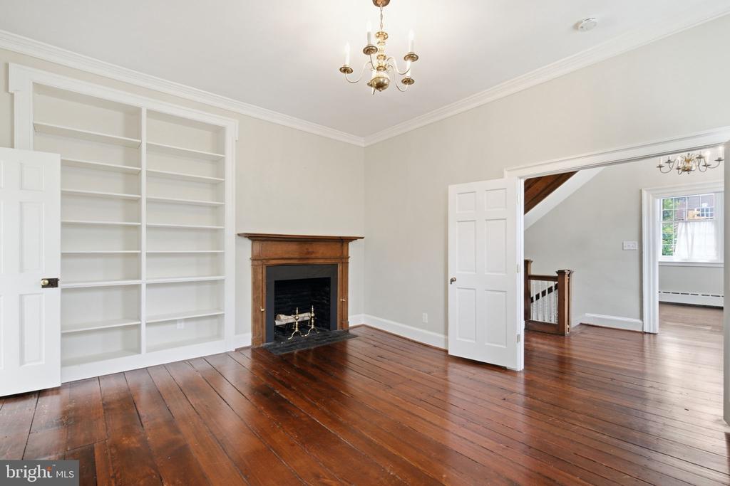 Living room with built-in bookshelves, a wood mantel fireplace, and dark hardwood floors.