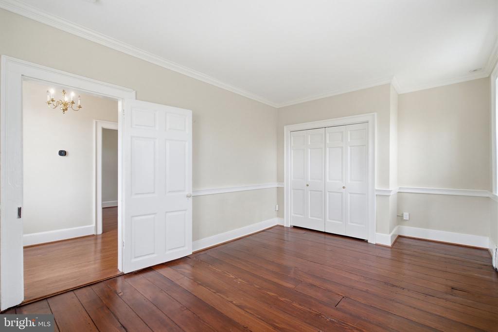 Empty room with polished hardwood floors, a paneled closet, and an open doorway.