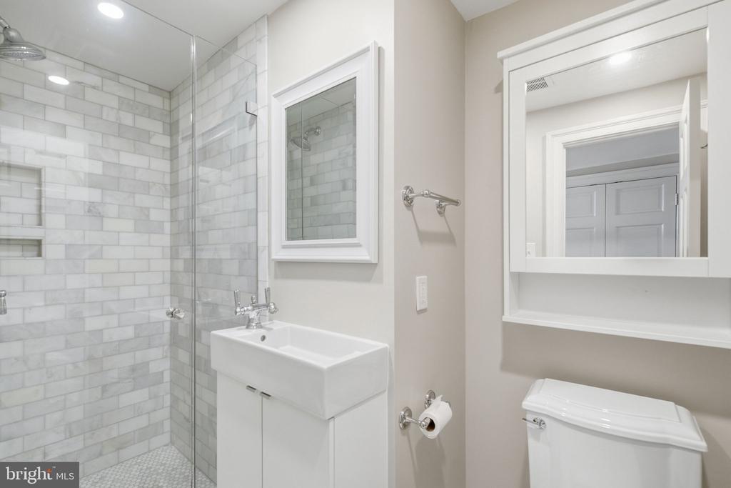 Bathroom with a glass shower, white subway tile, mosaic floor, sink vanity, and mirrored cabinet.