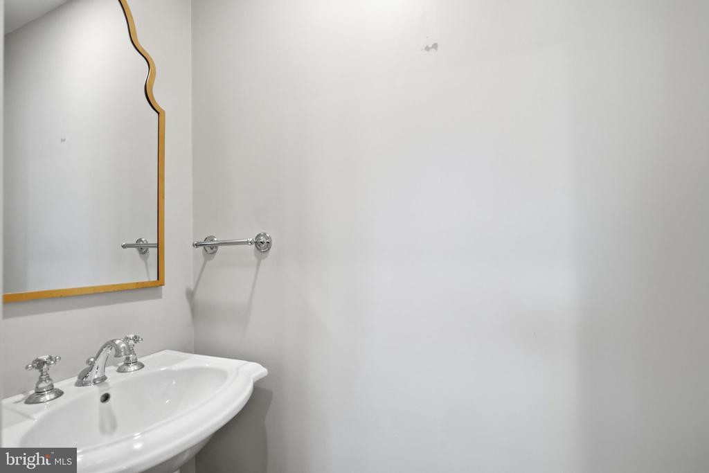 Bathroom sink with chrome faucets beneath a gold-framed mirror.