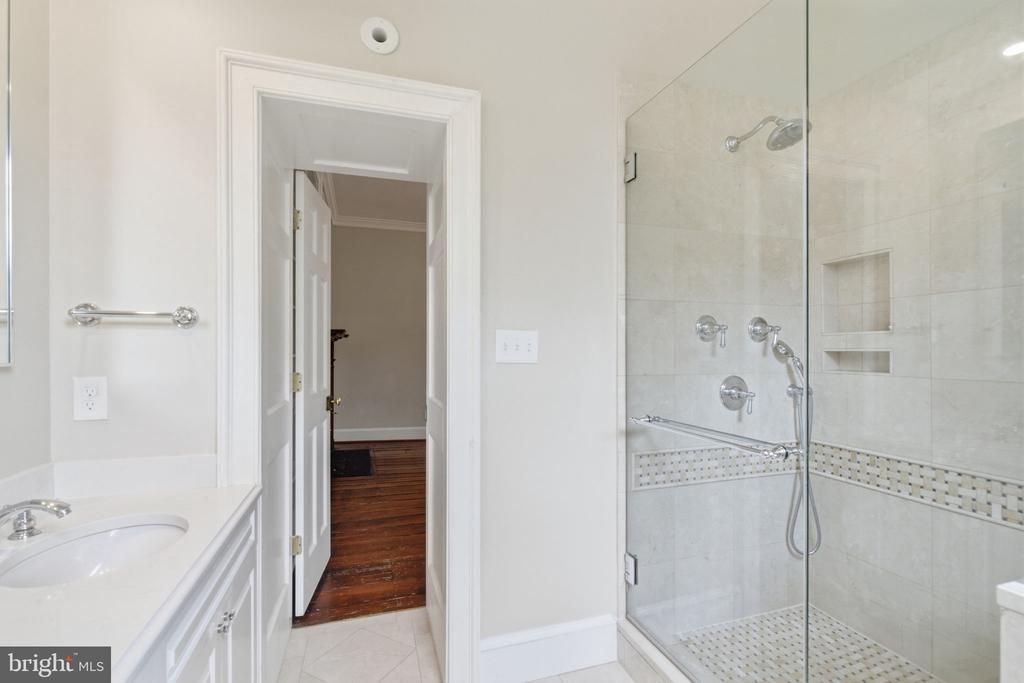 Bathroom with a glass-enclosed tiled shower, chrome fixtures, and a white vanity.