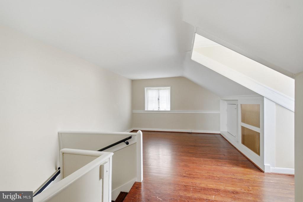 Finished attic loft with hardwood floors, a sloped ceiling, and a large skylight.