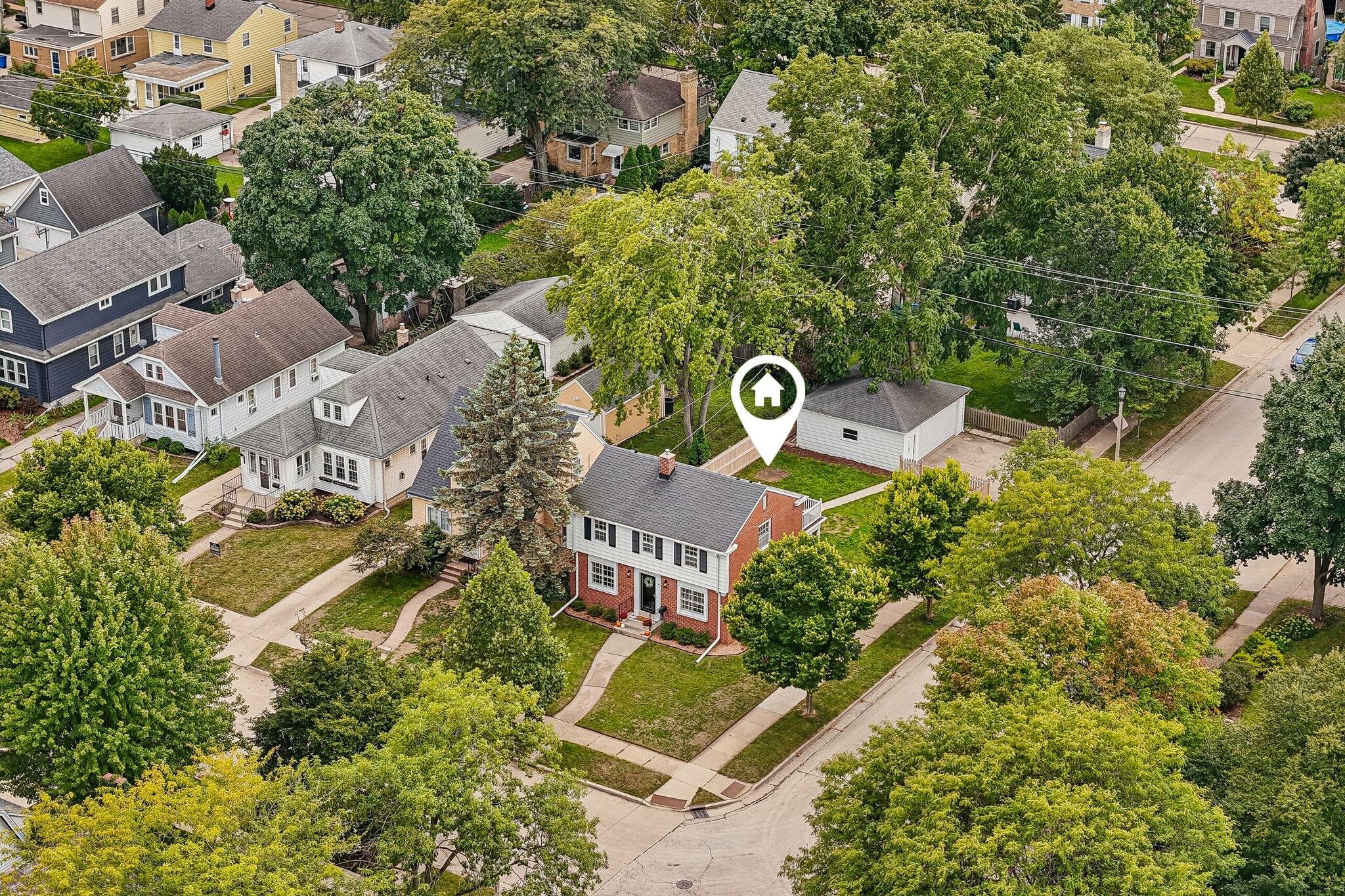 Aerial view of a leafy neighborhood, with a house marker above a property.