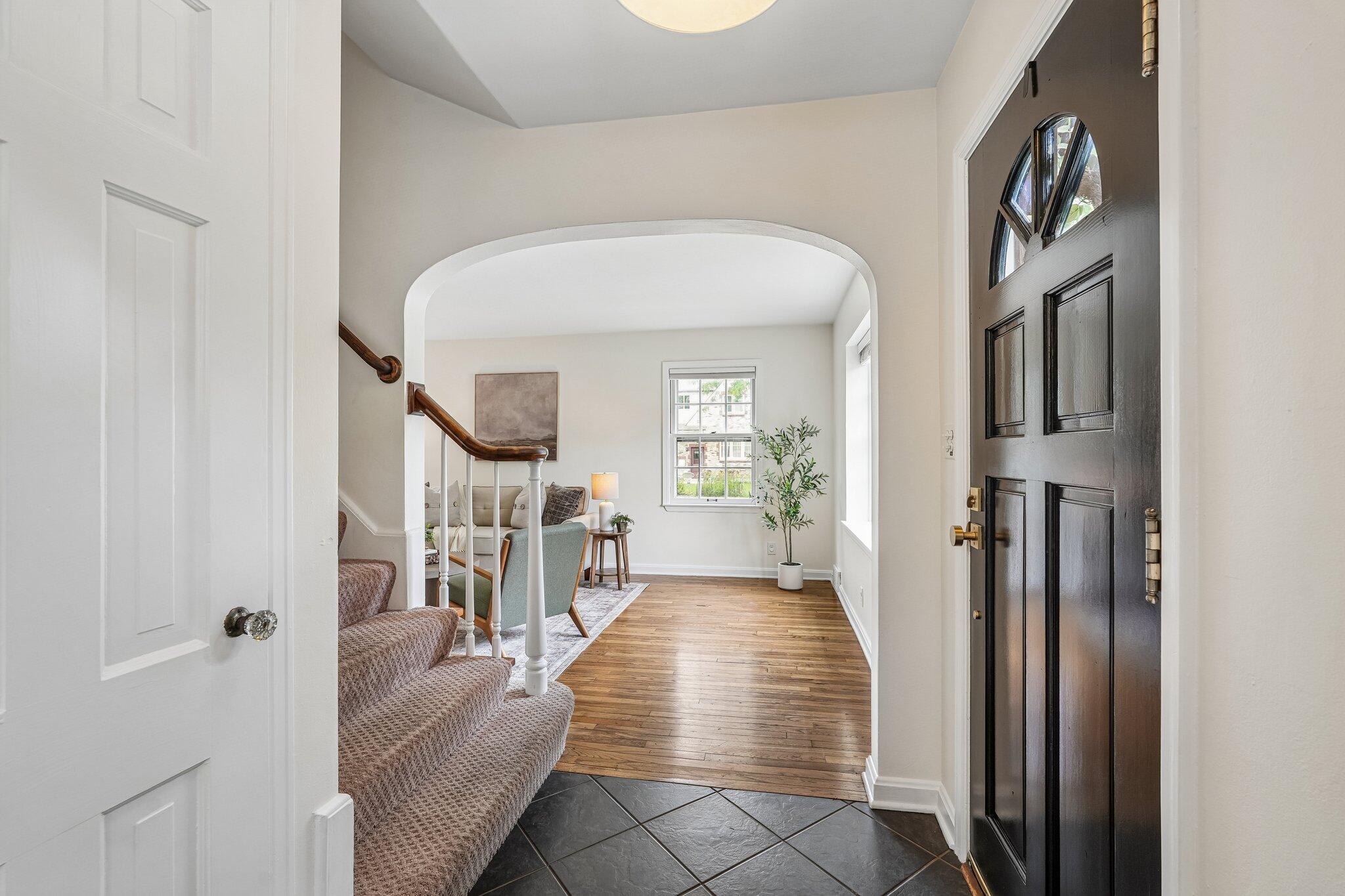 Entry foyer with a dark front door, slate tile, and an archway to the living room.