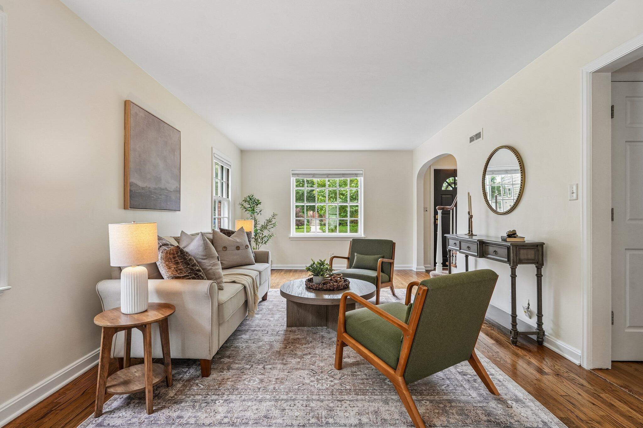 Bright living room with a cream sofa, green armchairs, and hardwood floors.