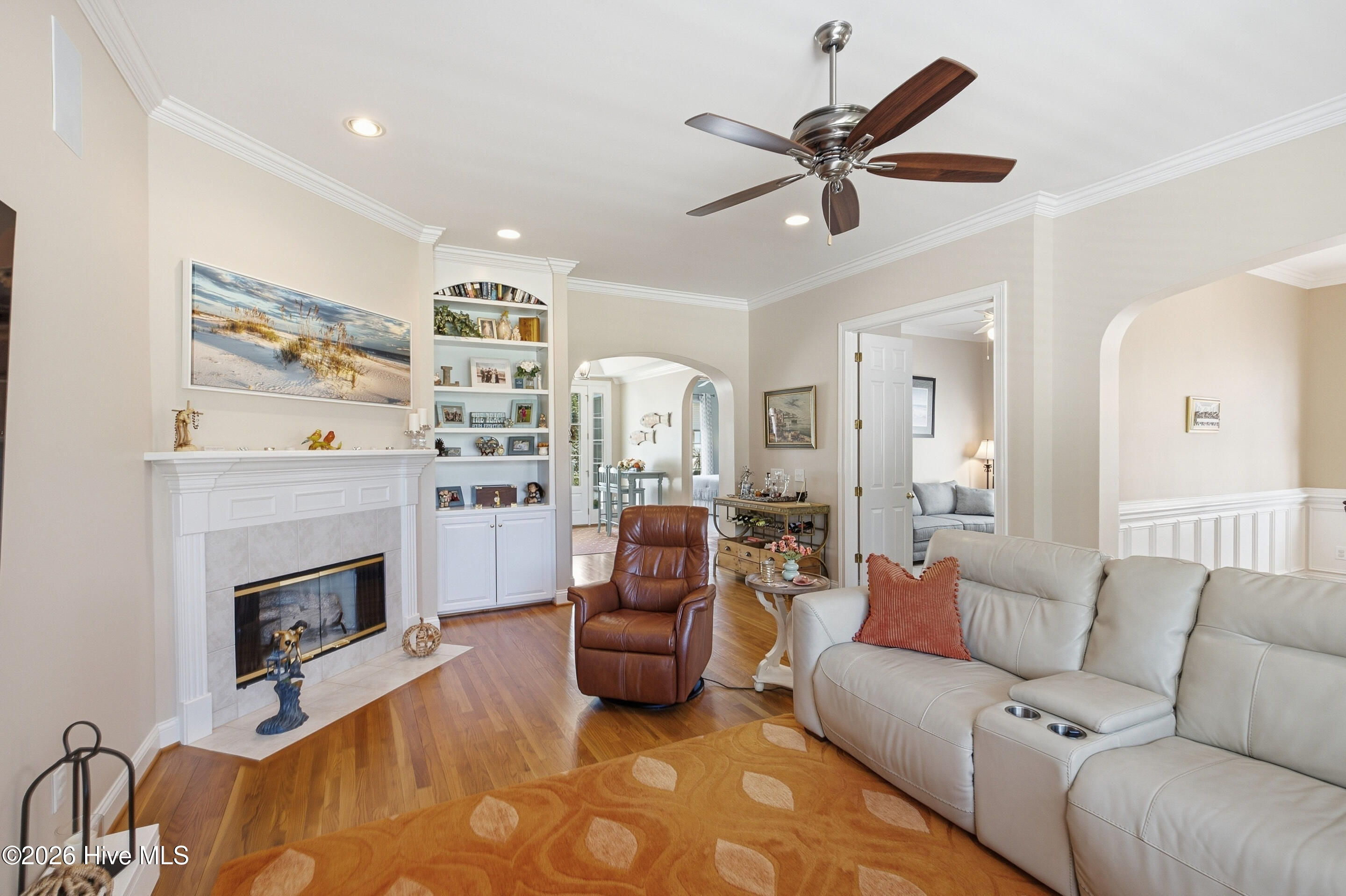 Living room with a white fireplace, built-in shelves, leather recliner, and light sectional sofa.