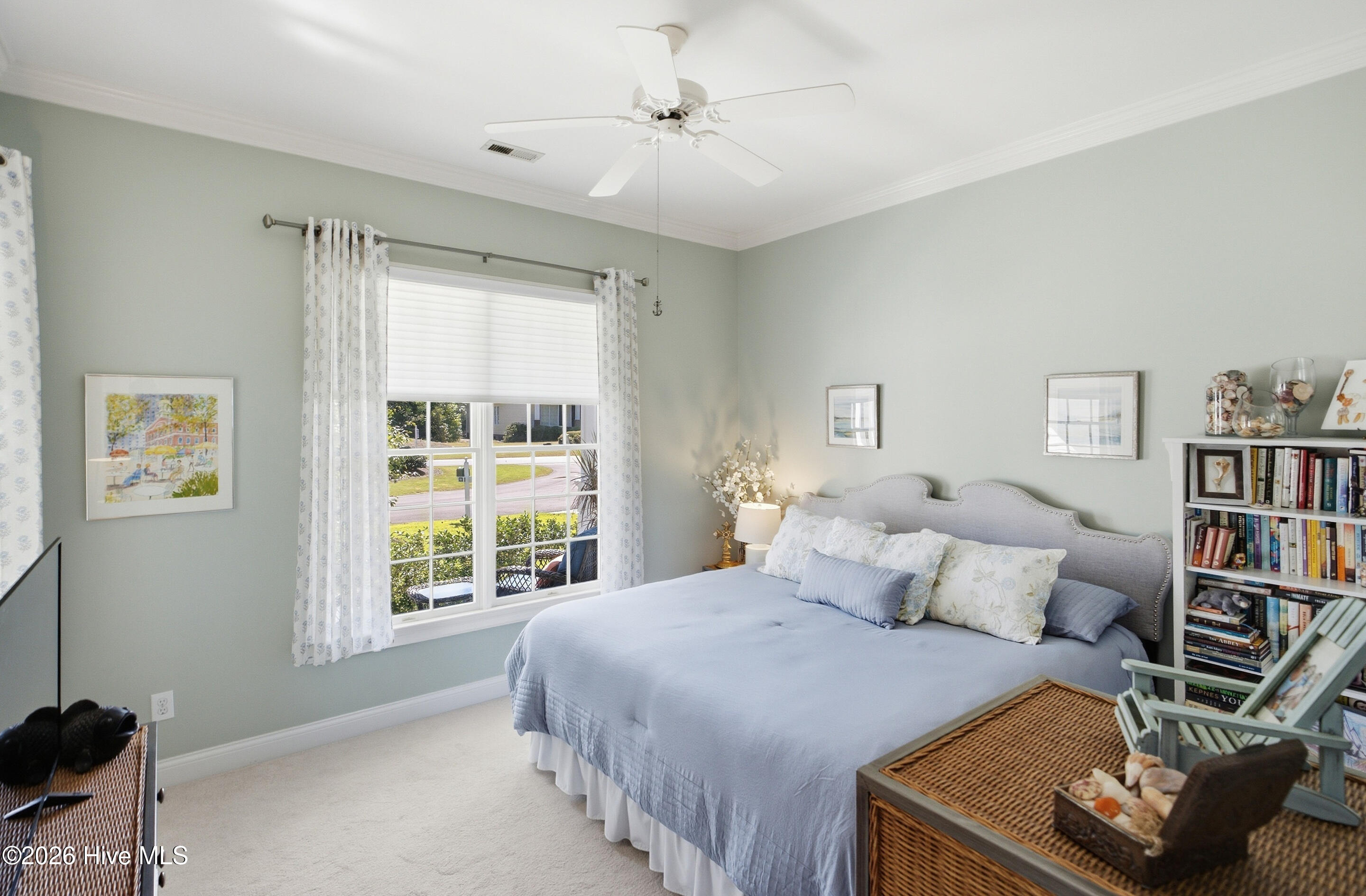 Bedroom with pale blue bedding, a gray upholstered headboard, and a large window with patterned curtains.