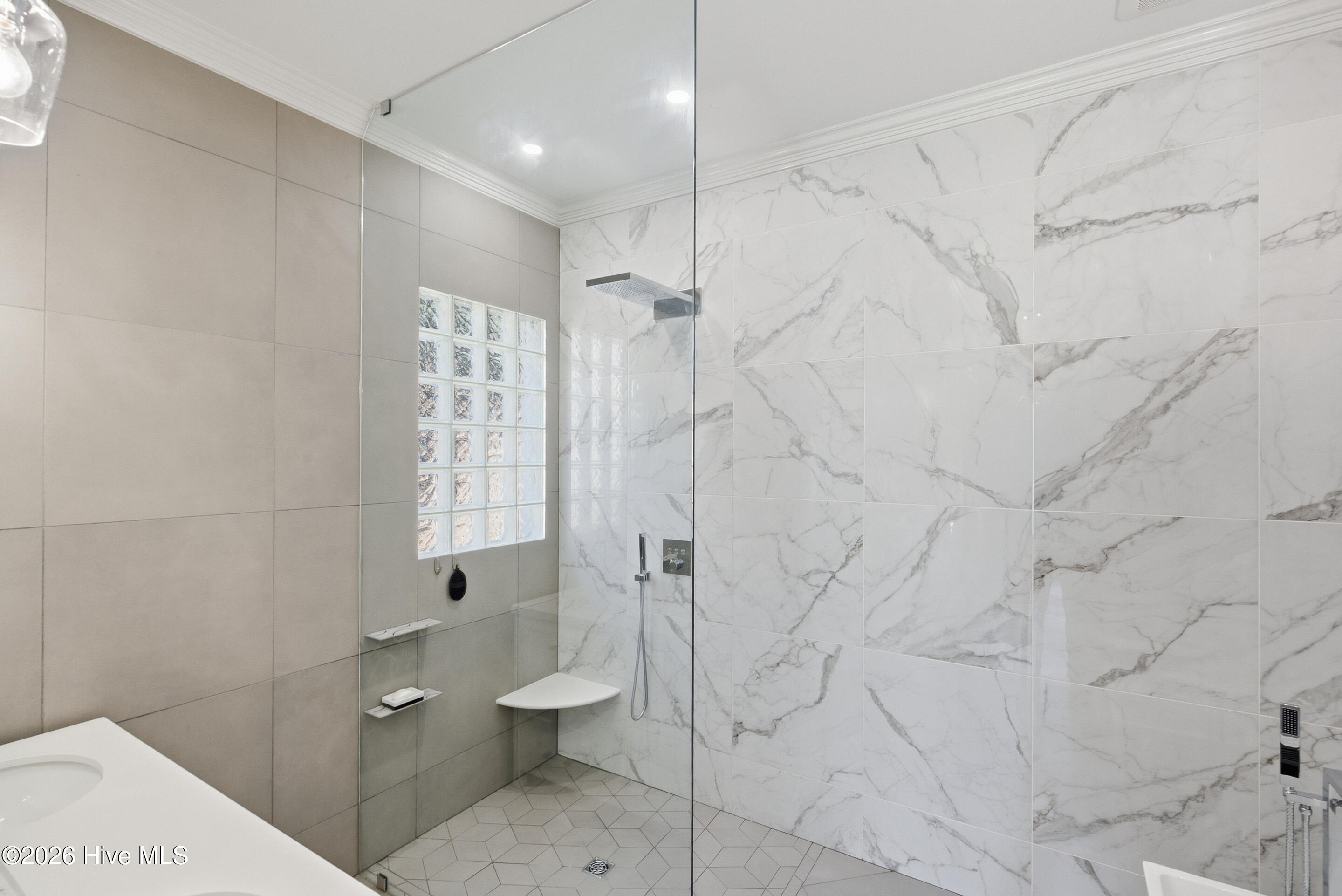 Bathroom with a glass-enclosed shower, marble-look tile, rainfall showerhead, and glass-block window.