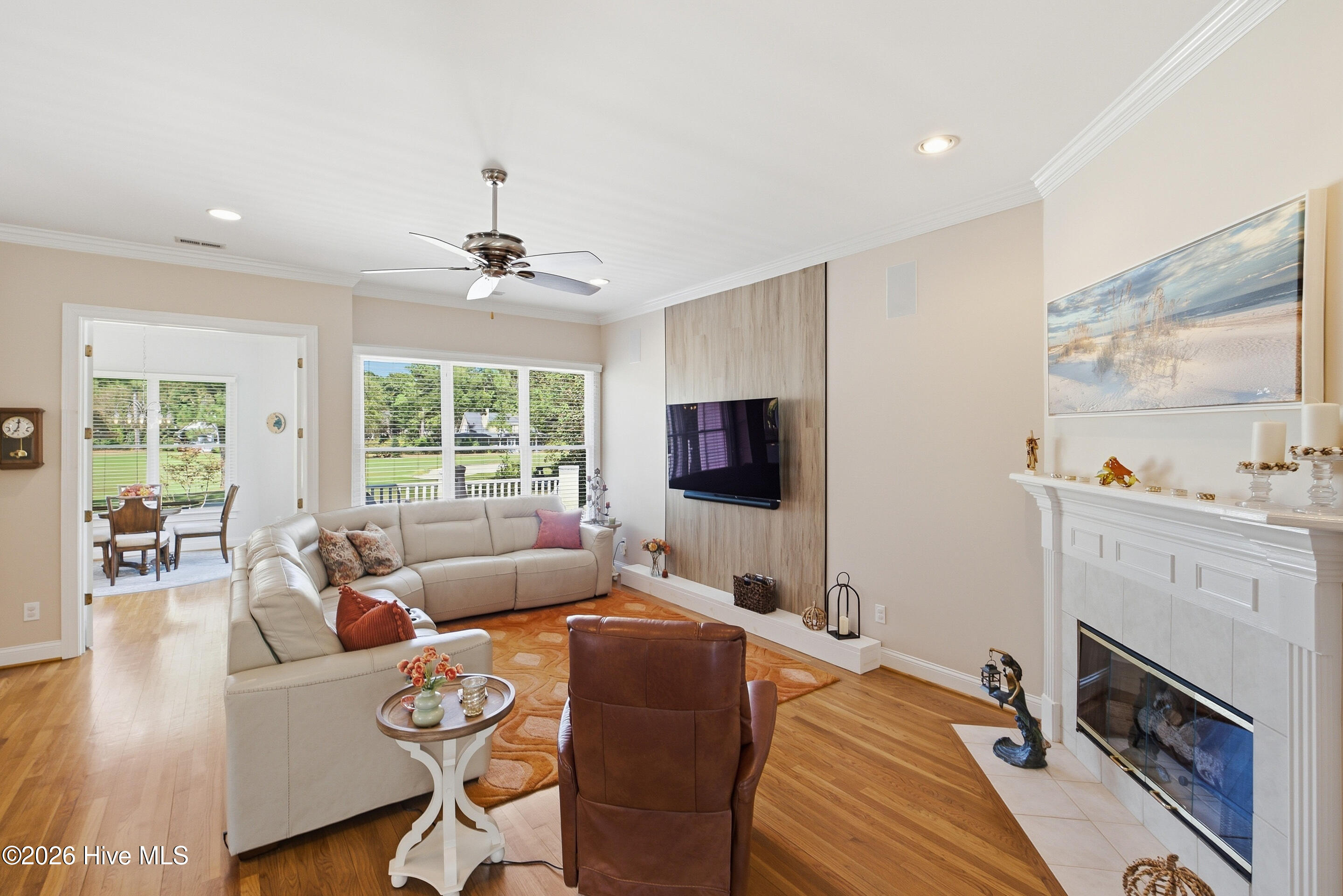 Living room with a cream sectional, wood accent wall, wall-mounted TV, and white fireplace.