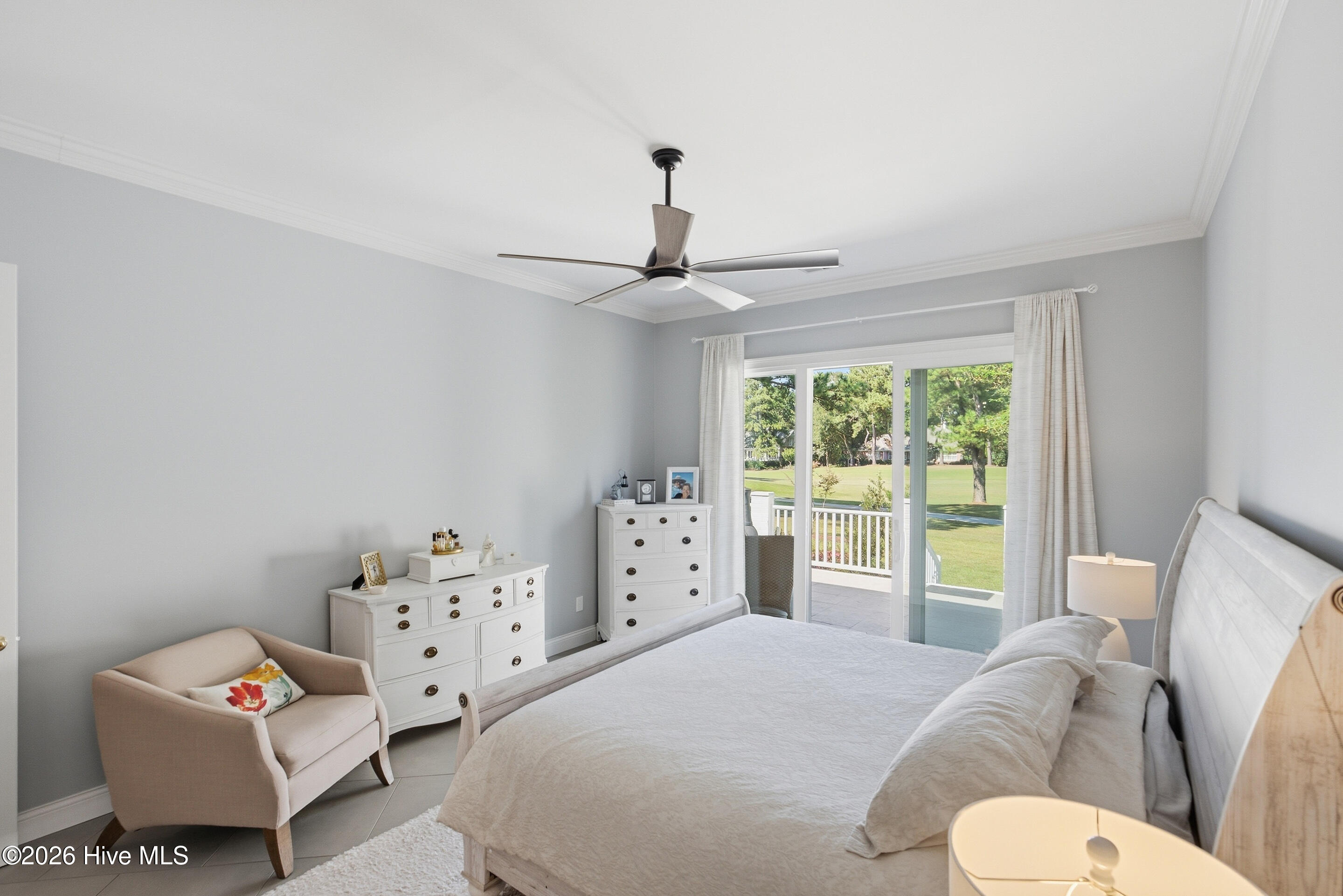 Bedroom with sliding glass doors opening onto a patio and green lawn.