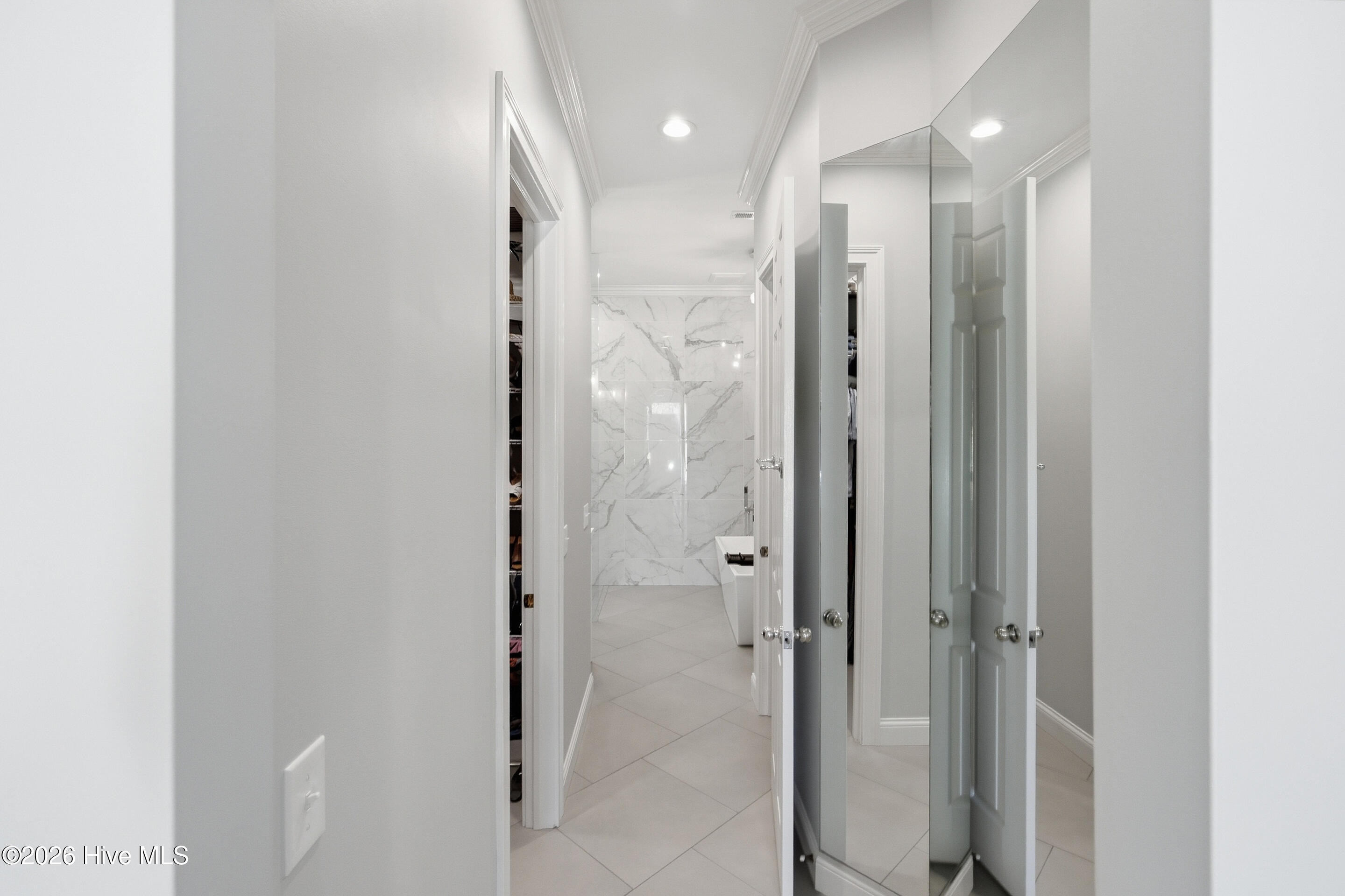 Bathroom with marble-look shower wall, pale tile flooring, and mirrored closet doors.