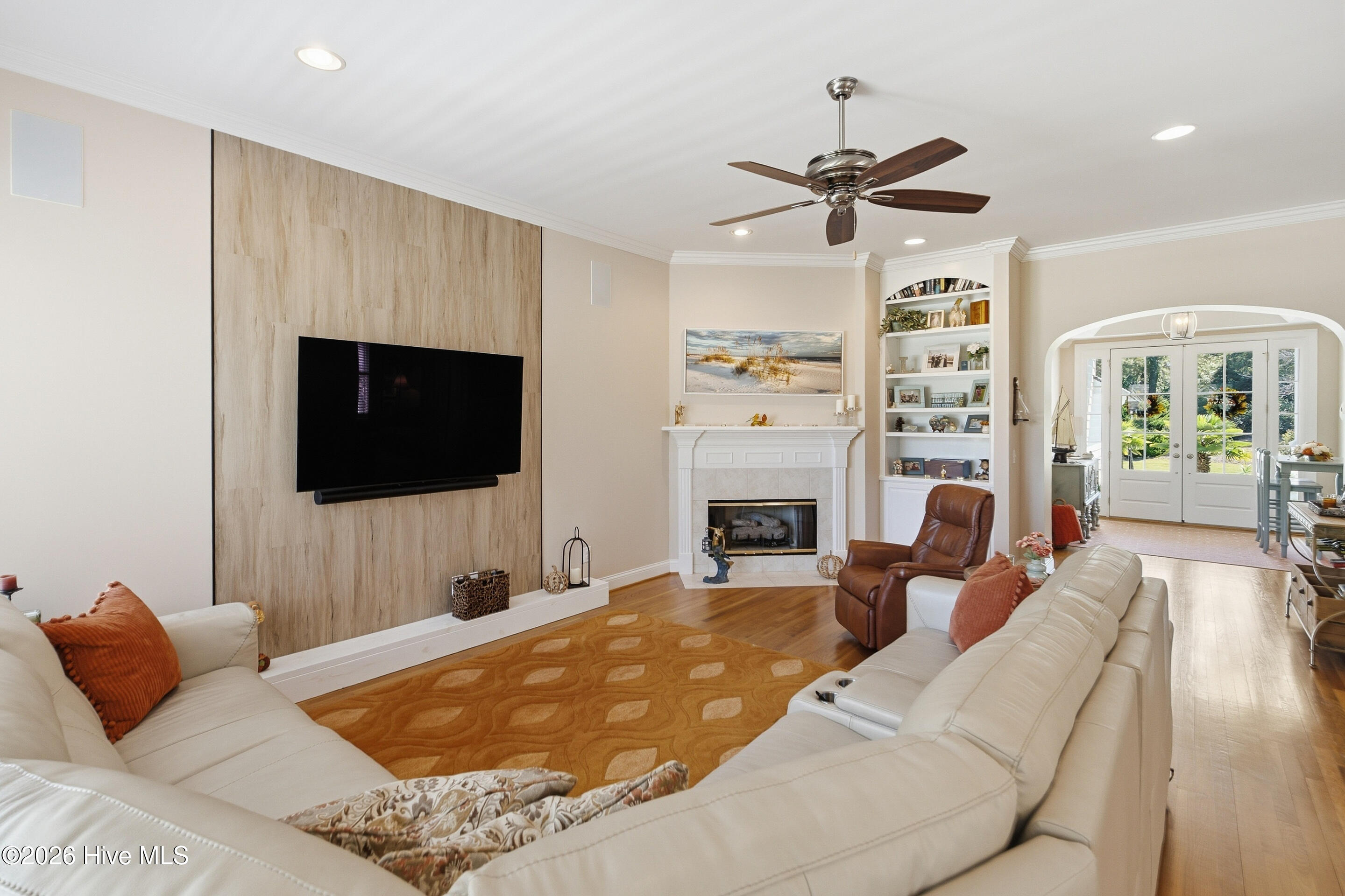 Living room with sectional sofa, wood-look TV wall, fireplace, and French doors to the garden.