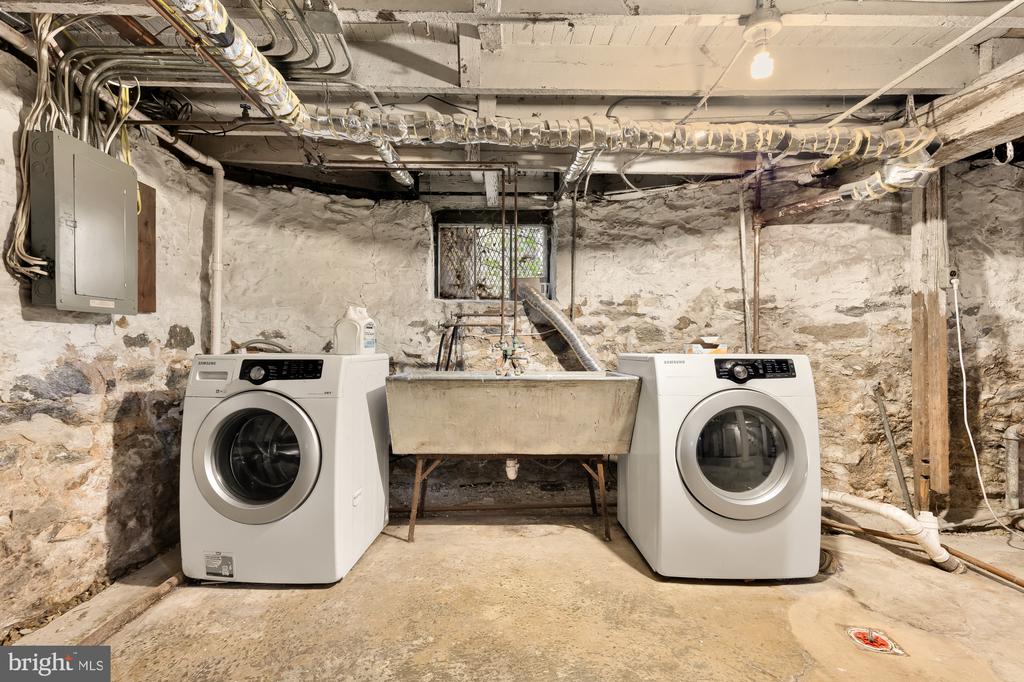 Basement laundry room with two front-loading machines and a deep utility sink.