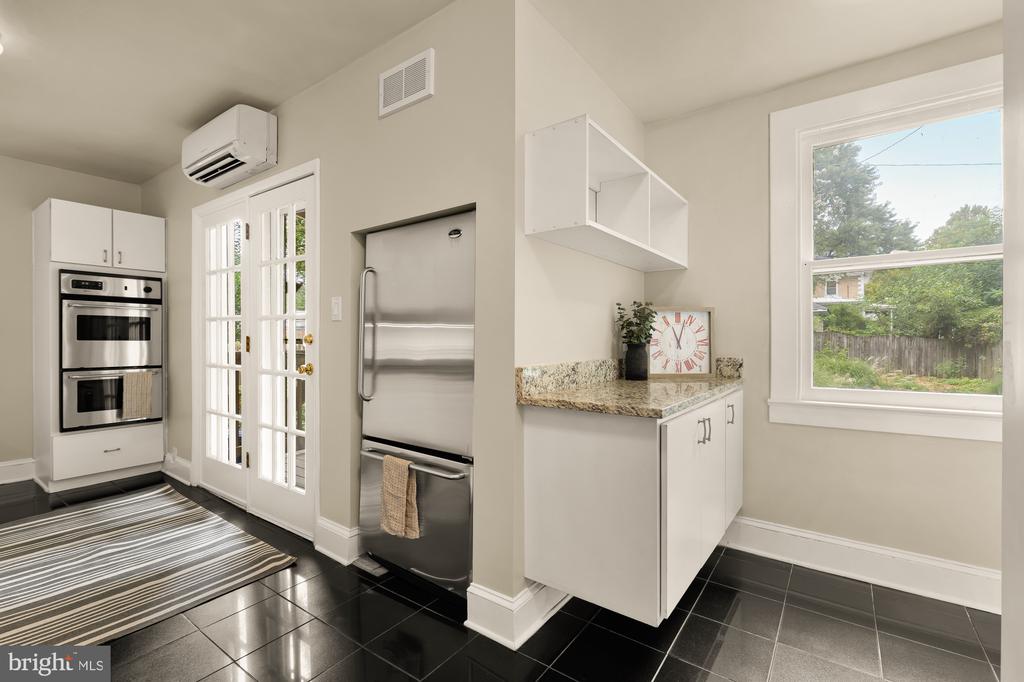 Kitchen with white cabinetry, stainless steel appliances, black tile flooring, and French doors.