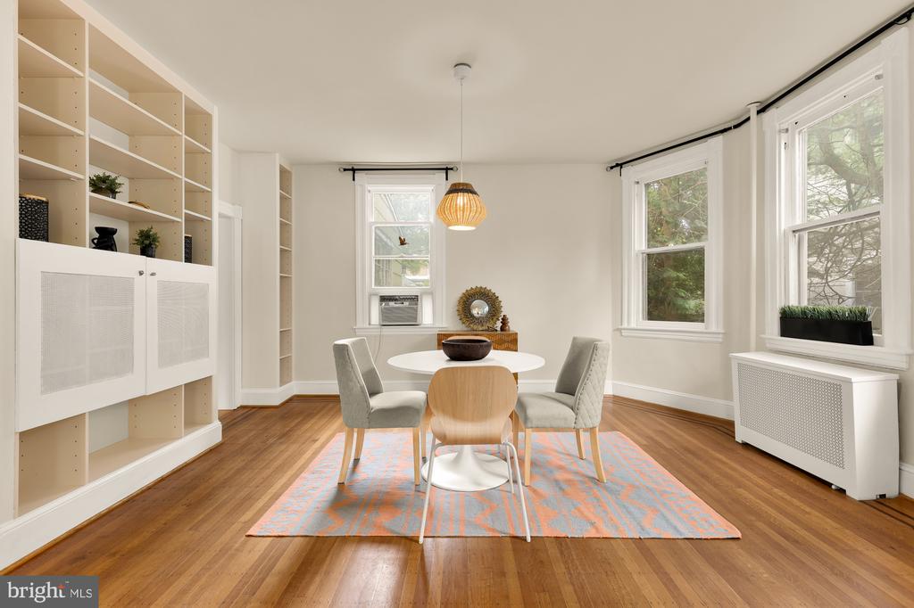 Dining room with built-in shelving, a round table, four chairs, and tall windows.