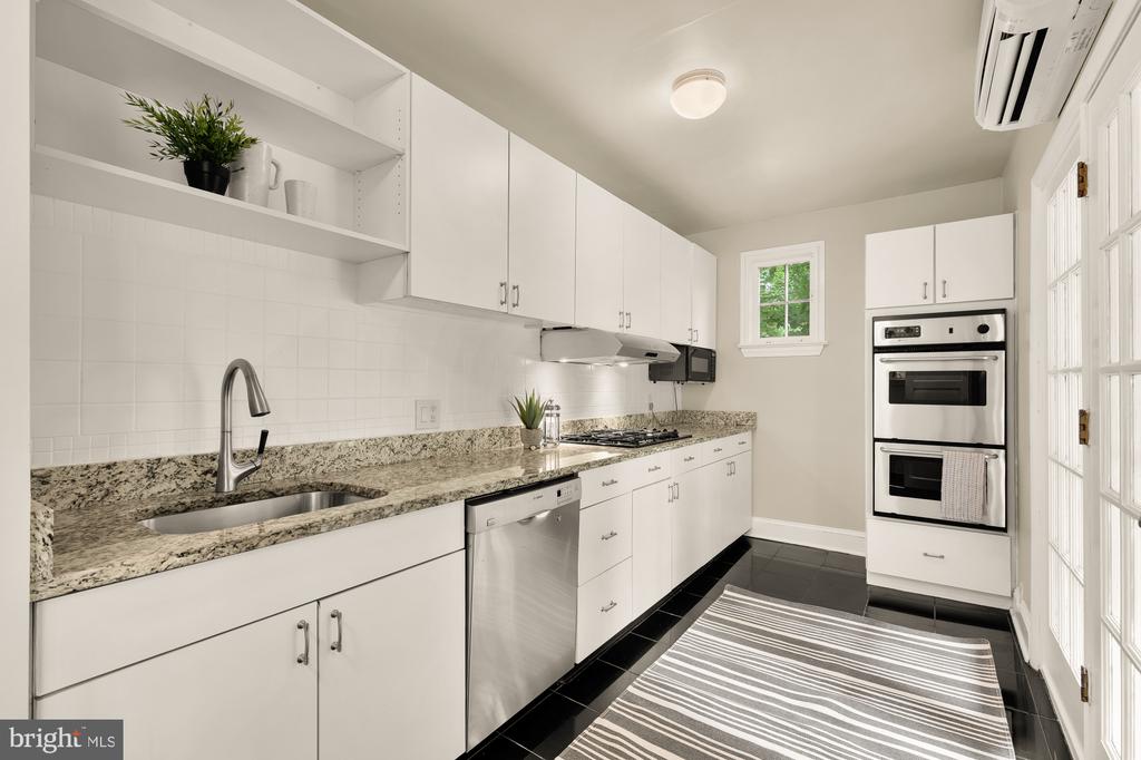 Kitchen with white cabinetry, granite counters, stainless appliances, and a striped runner.
