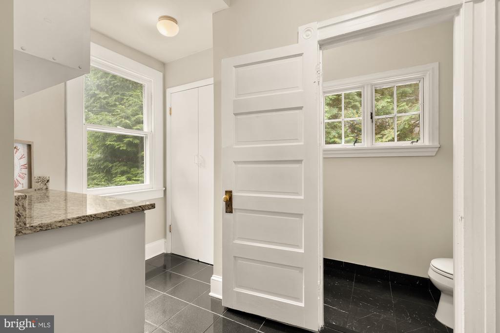 Bathroom with a granite vanity, dark tile floors, and a separate toilet area.