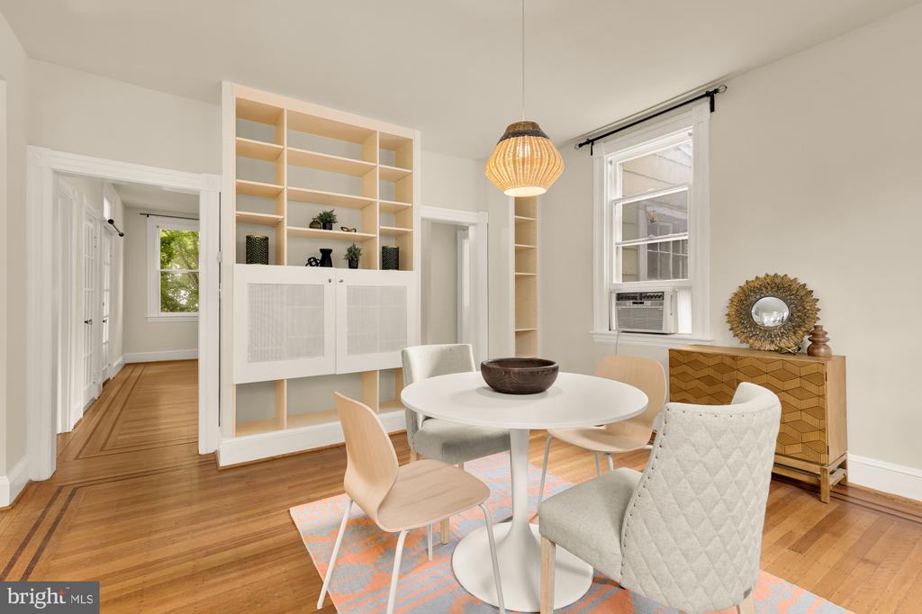 Dining room with built-in shelving, a round table, hardwood floors, and a woven pendant light.