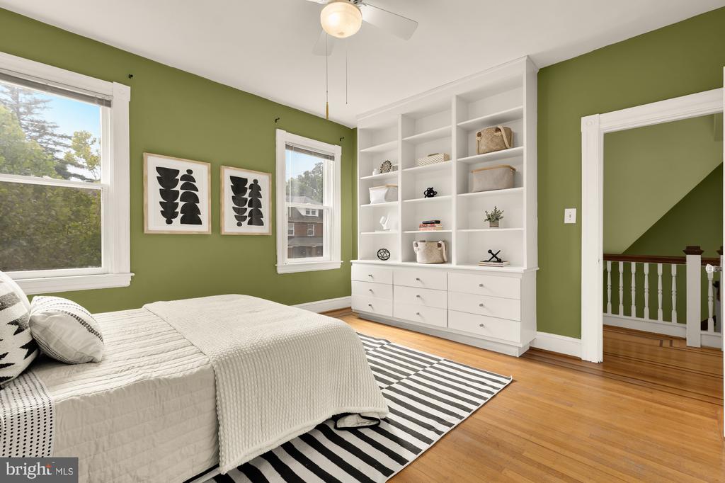 Bedroom with olive-green walls, built-in white shelving, a white bed, and a striped rug.