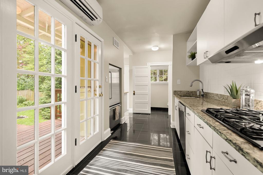 Kitchen with white cabinets, granite counters, gas range, and glass-paneled doors opening to a deck.